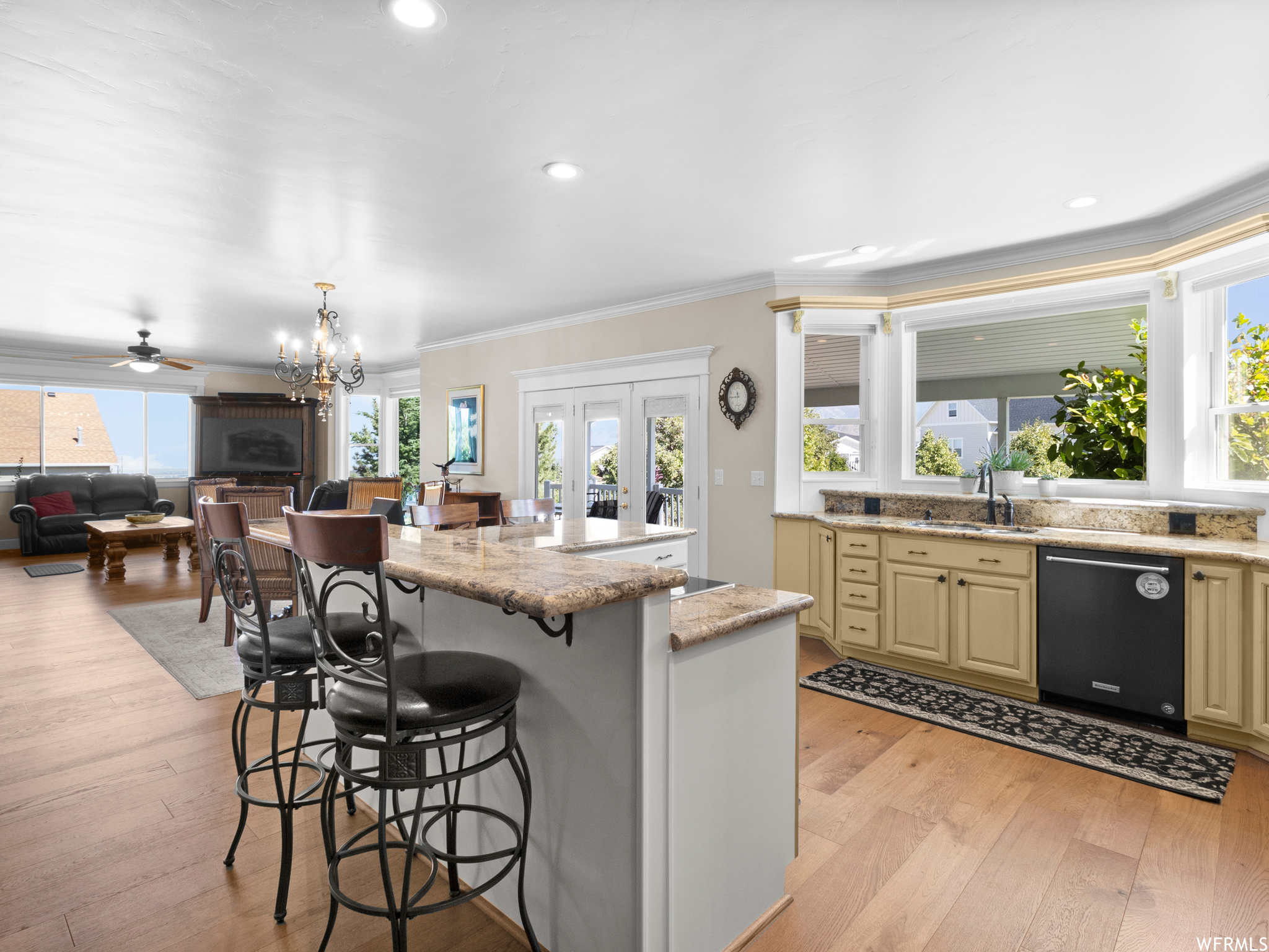 Kitchen featuring a kitchen island, plenty of natural light, black dishwasher, a chandelier, light hardwood flooring, and ornamental molding