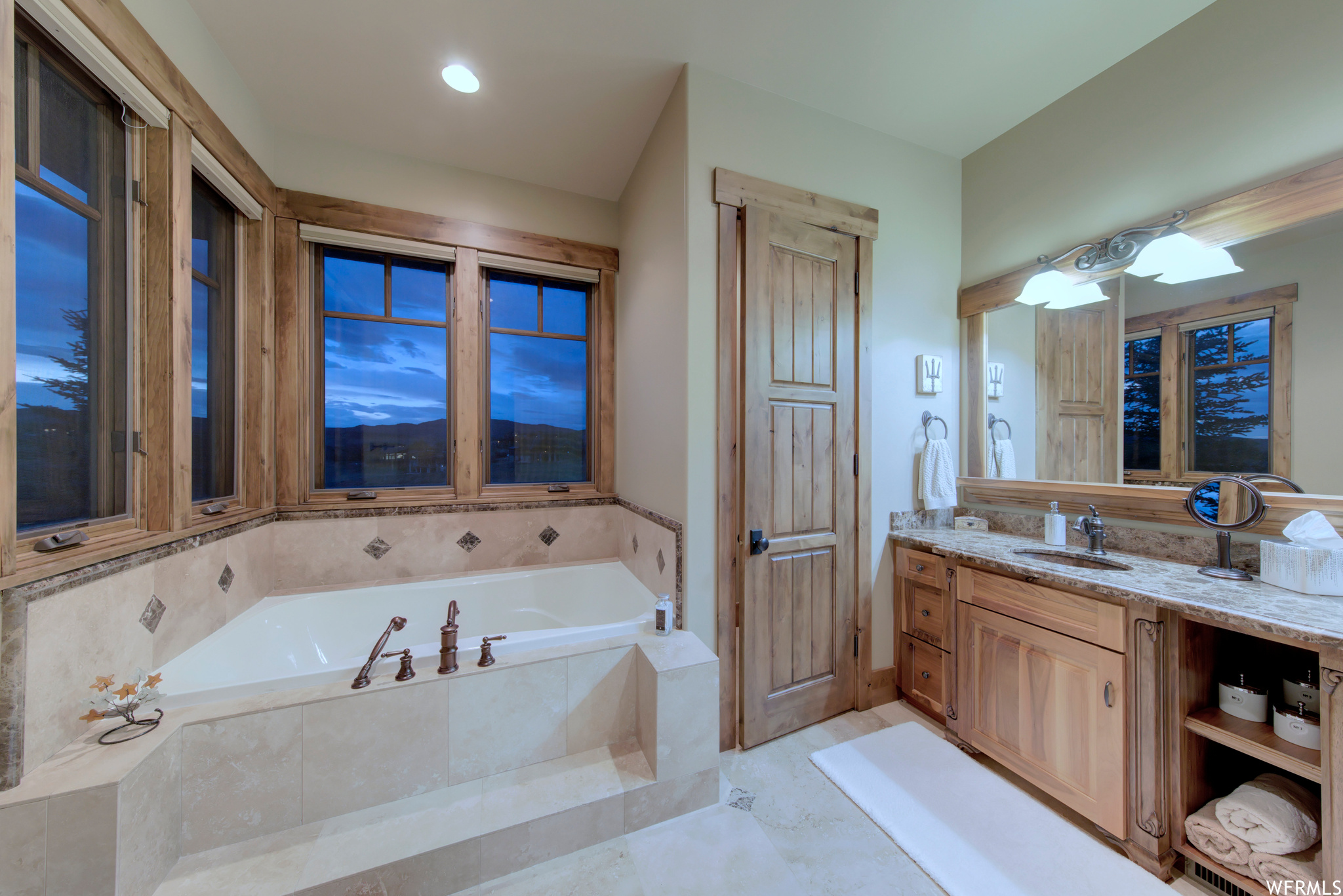 2nd main floor master bathroom with vanity with extensive cabinet space, tiled bath, mirror, and light tile floors