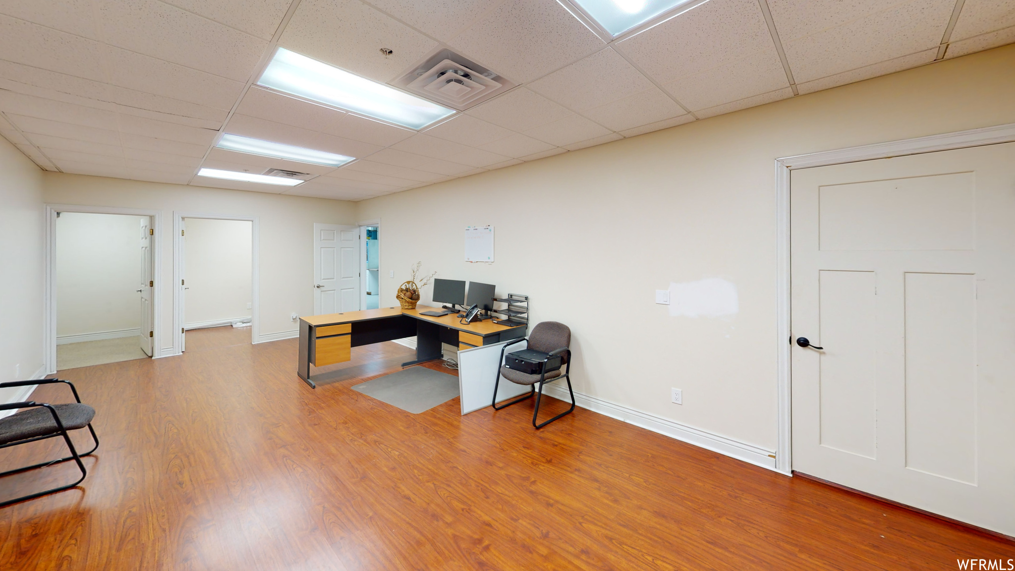 Hardwood floored office space with a drop ceiling