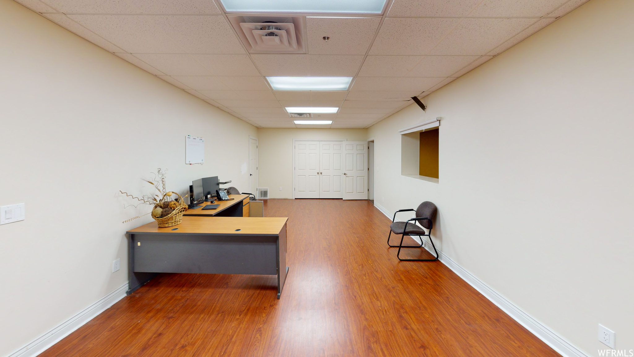 Office area featuring a drop ceiling and light hardwood flooring