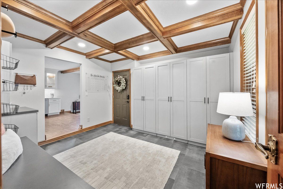 Interior space with coffered ceiling, beamed ceiling, and light hardwood flooring