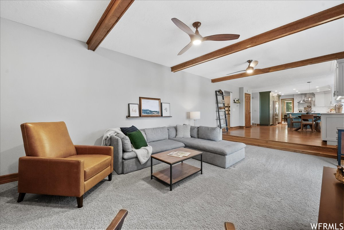 Carpeted living room featuring beam ceiling