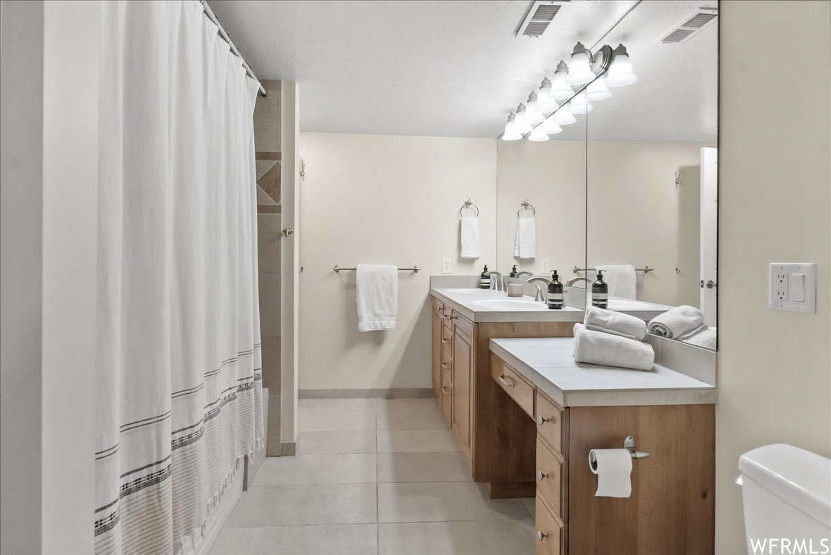 Bathroom featuring mirror, light tile floors, and vanity
