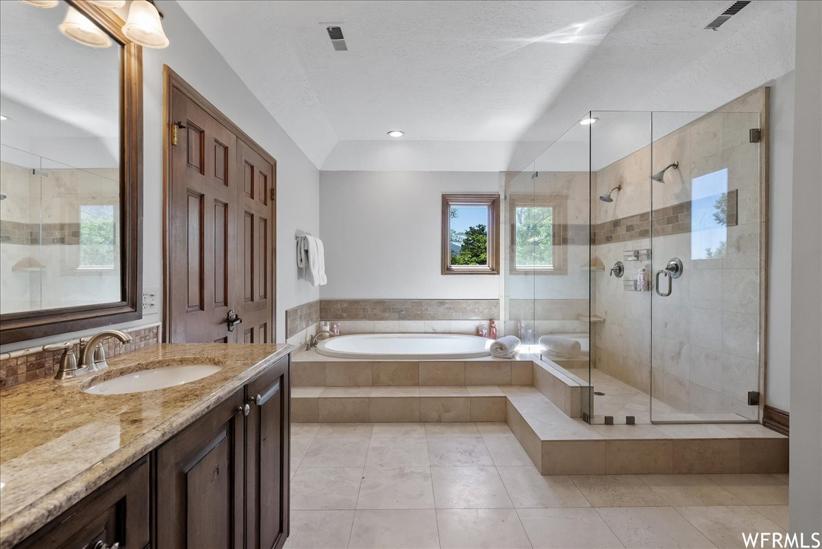 Bathroom with separate shower and tub enclosures, oversized vanity, mirror, and light tile floors