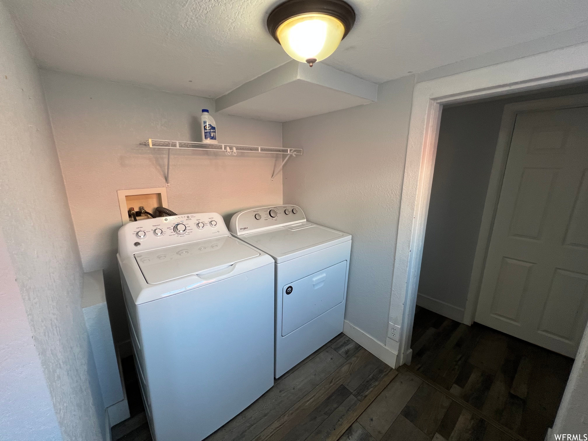 Washroom with dark laminate floors and washer and dryer