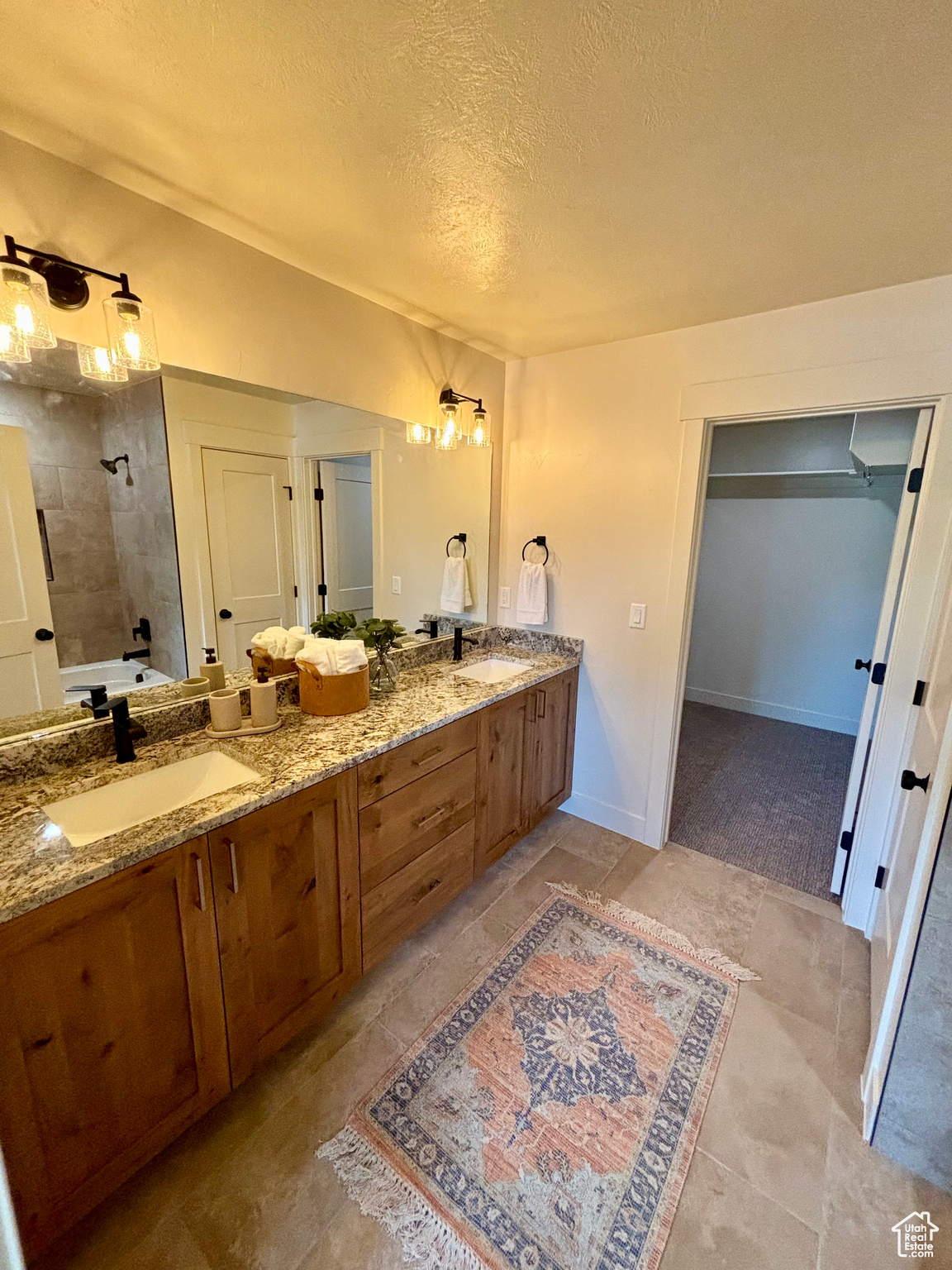 Bathroom with a textured ceiling, a tile shower, and vanity