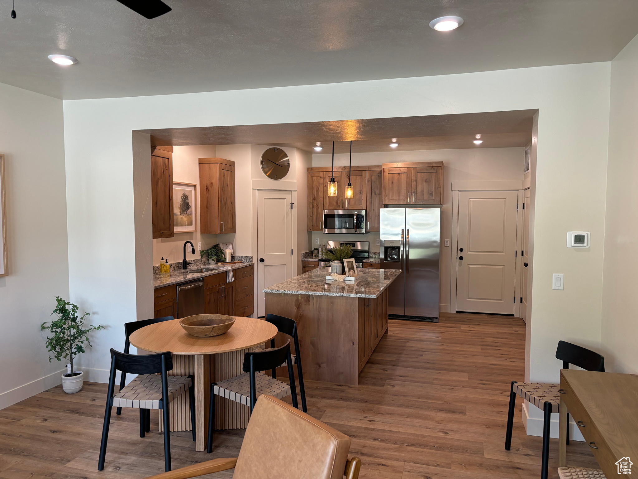 Kitchen featuring pendant lighting, sink, appliances with stainless steel finishes, a center island, and hardwood / wood-style floors