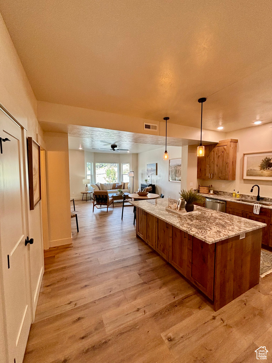 Kitchen with ceiling fan, sink, a kitchen island, decorative light fixtures, and light hardwood / wood-style floors