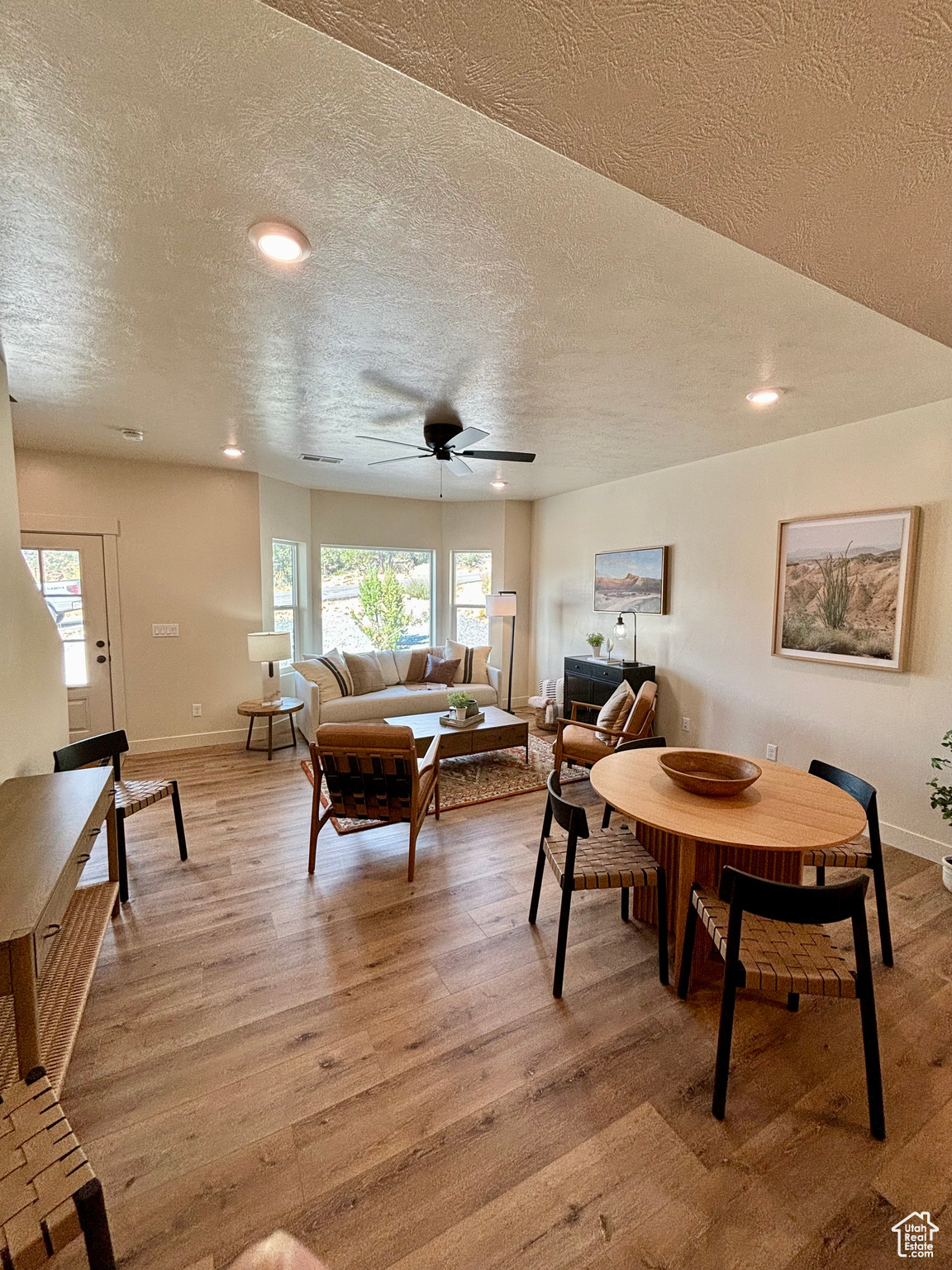 Dining room with light hardwood / wood-style flooring, ceiling fan, and a textured ceiling