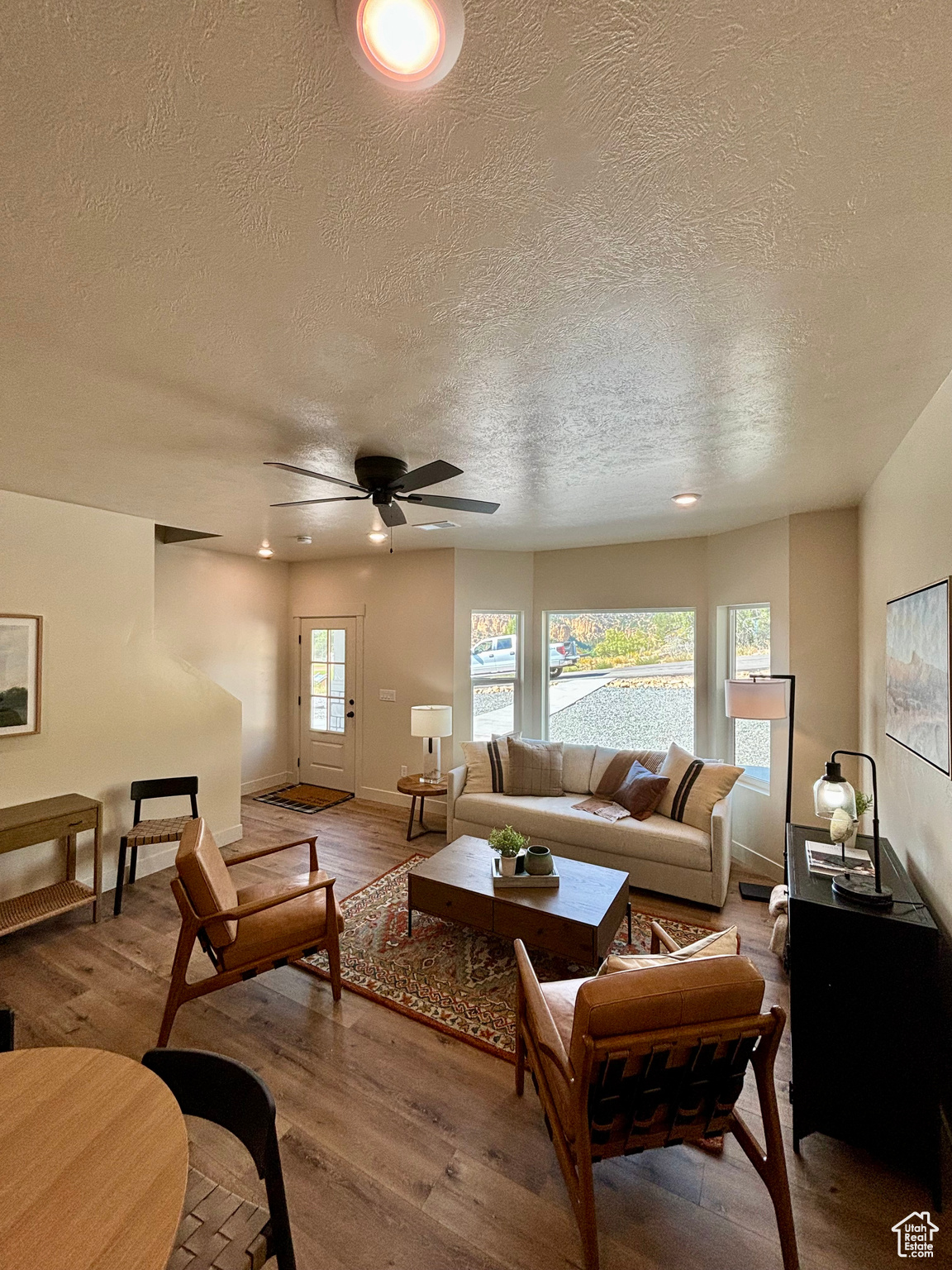 Living room with ceiling fan, hardwood / wood-style flooring, and a textured ceiling