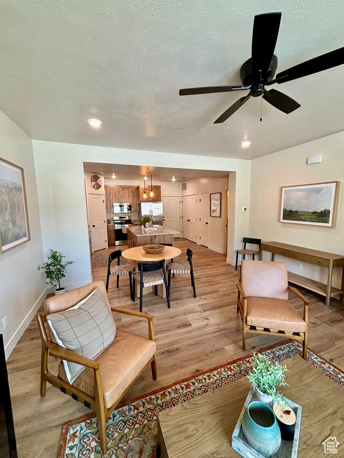 Living room featuring a textured ceiling, light hardwood / wood-style floors, and ceiling fan