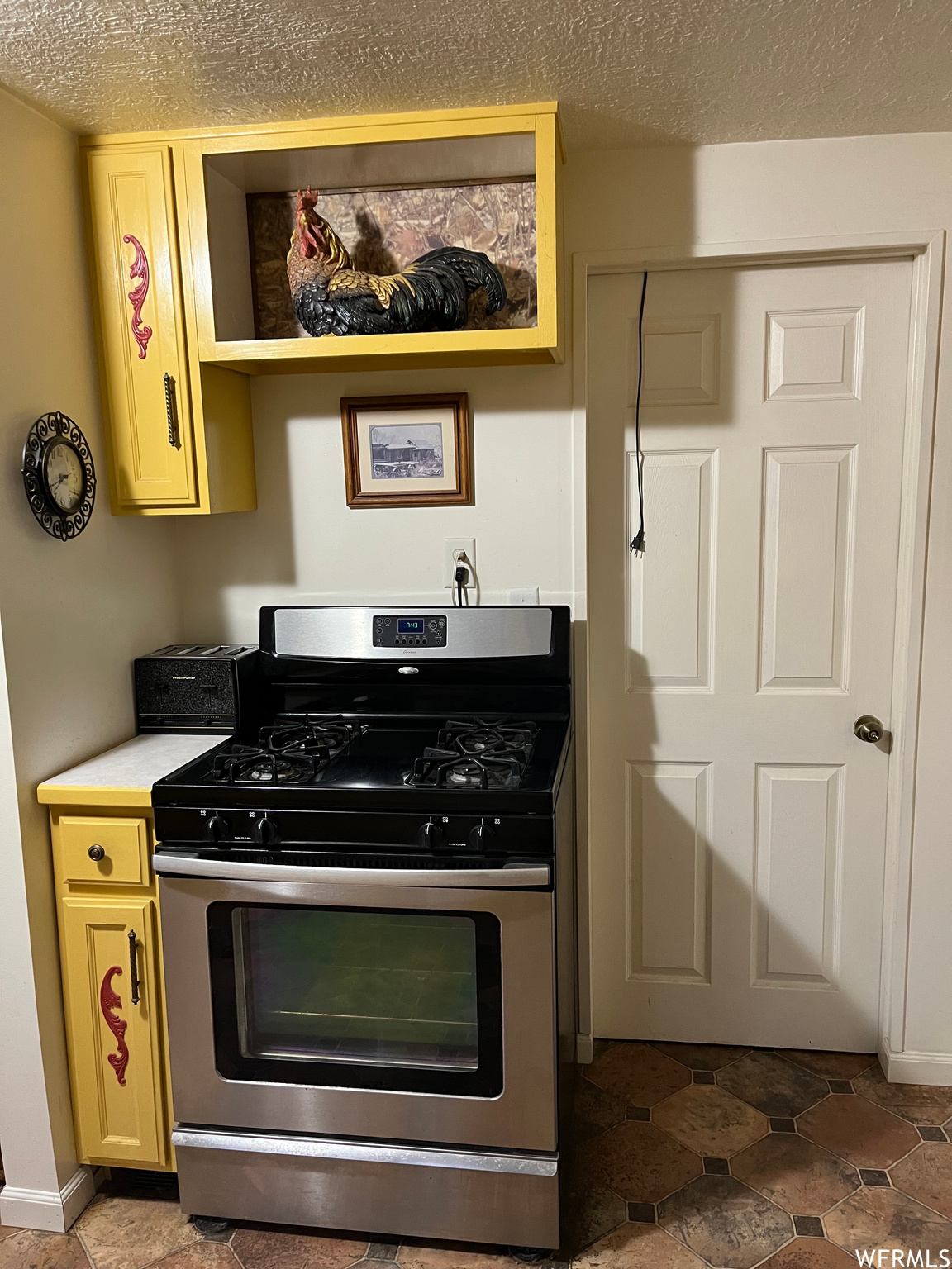 Kitchen with dark tile floors, stainless steel gas range and oven.