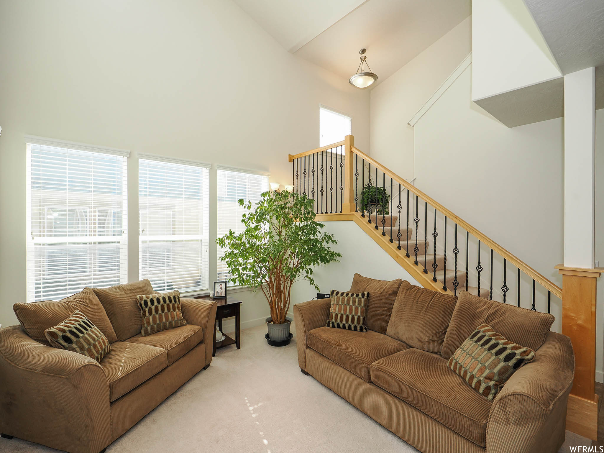 Living room with a high ceiling, light carpet, and lofted ceiling