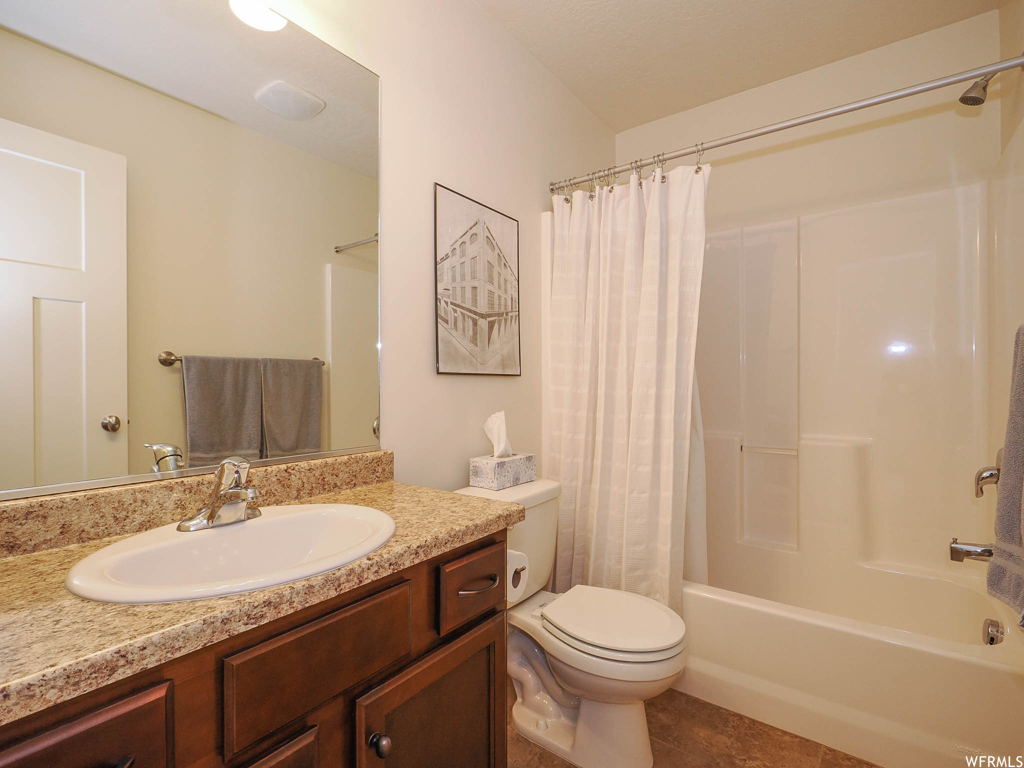 Full bathroom featuring oversized vanity, shower / bath combo, mirror, and light tile flooring