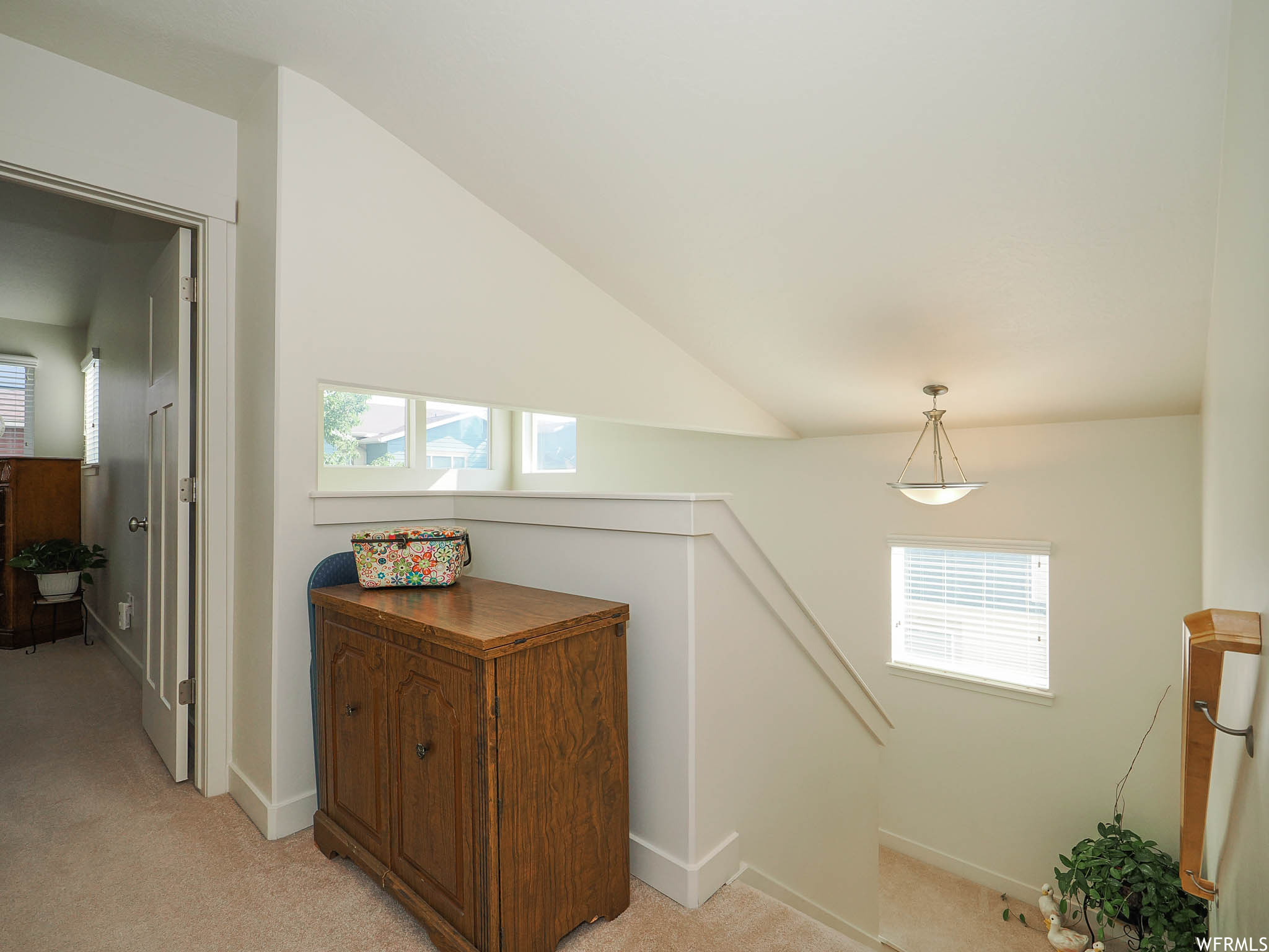 Corridor featuring vaulted ceiling and light carpet