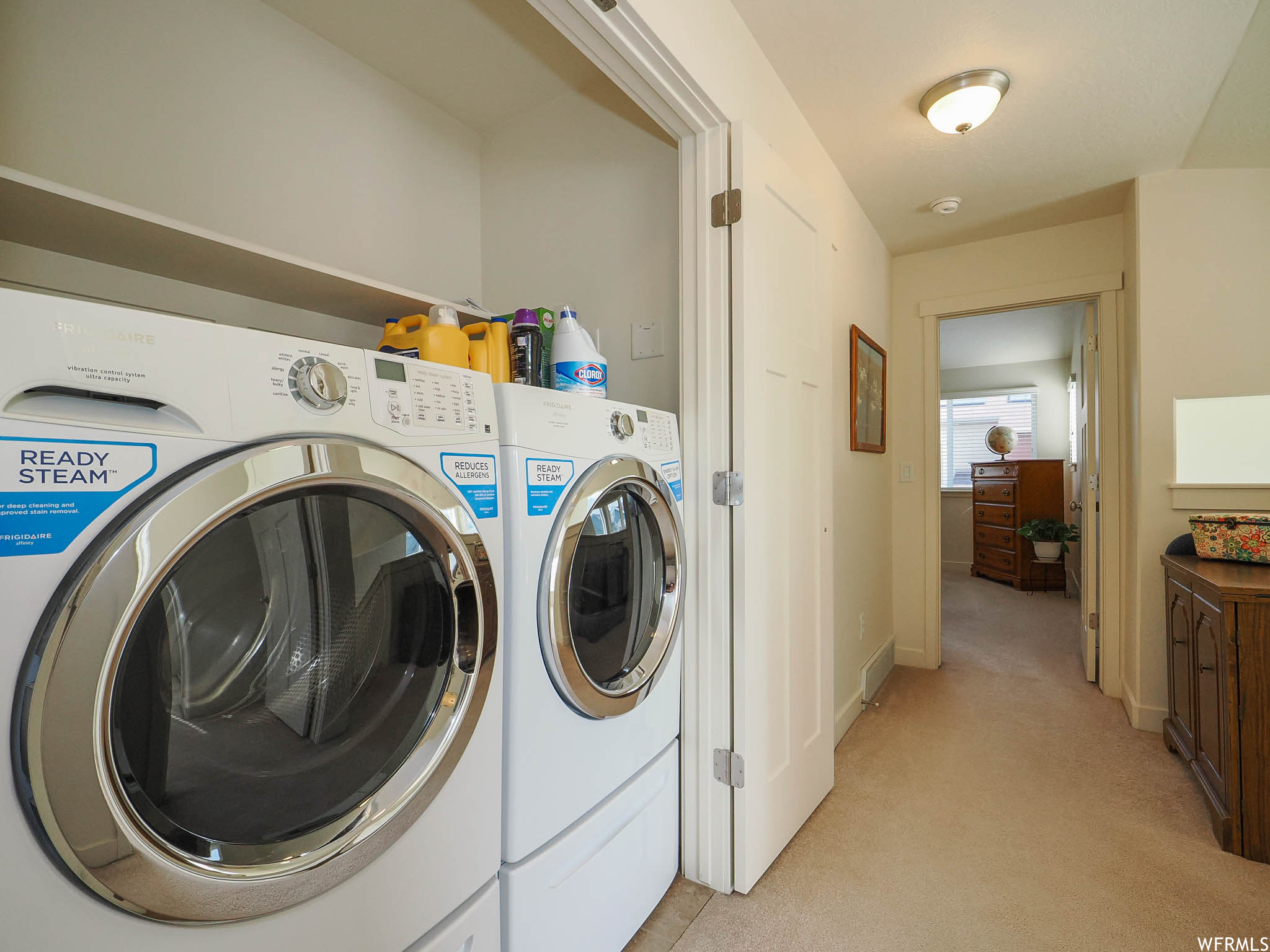 Washroom featuring washing machine and dryer and light carpet