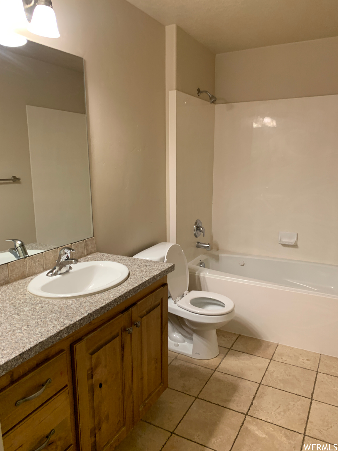 Full bathroom with washtub / shower combination, oversized vanity, light tile flooring, and mirror