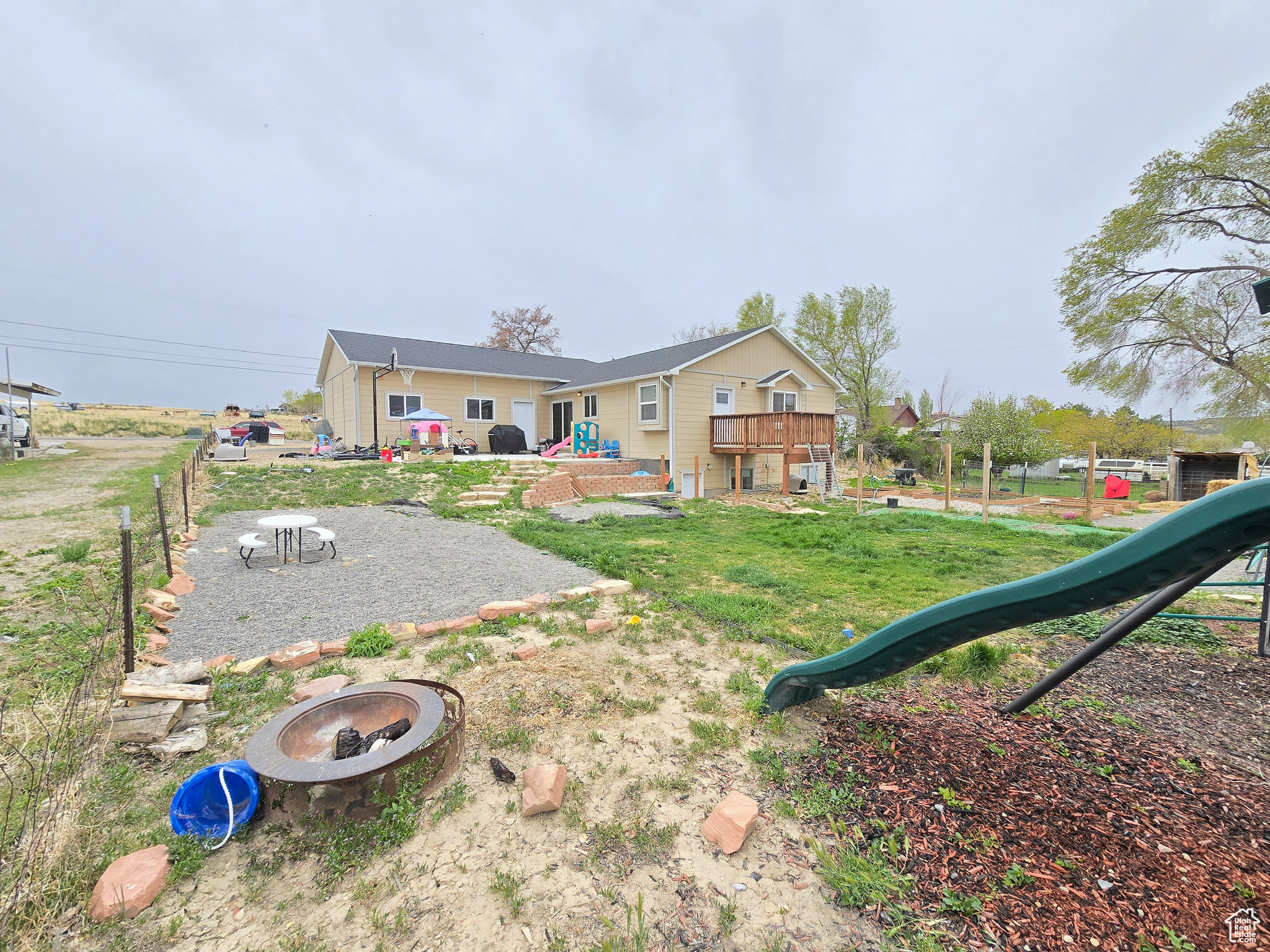 Rear view of house featuring a wooden deck, a fire pit, and a yard