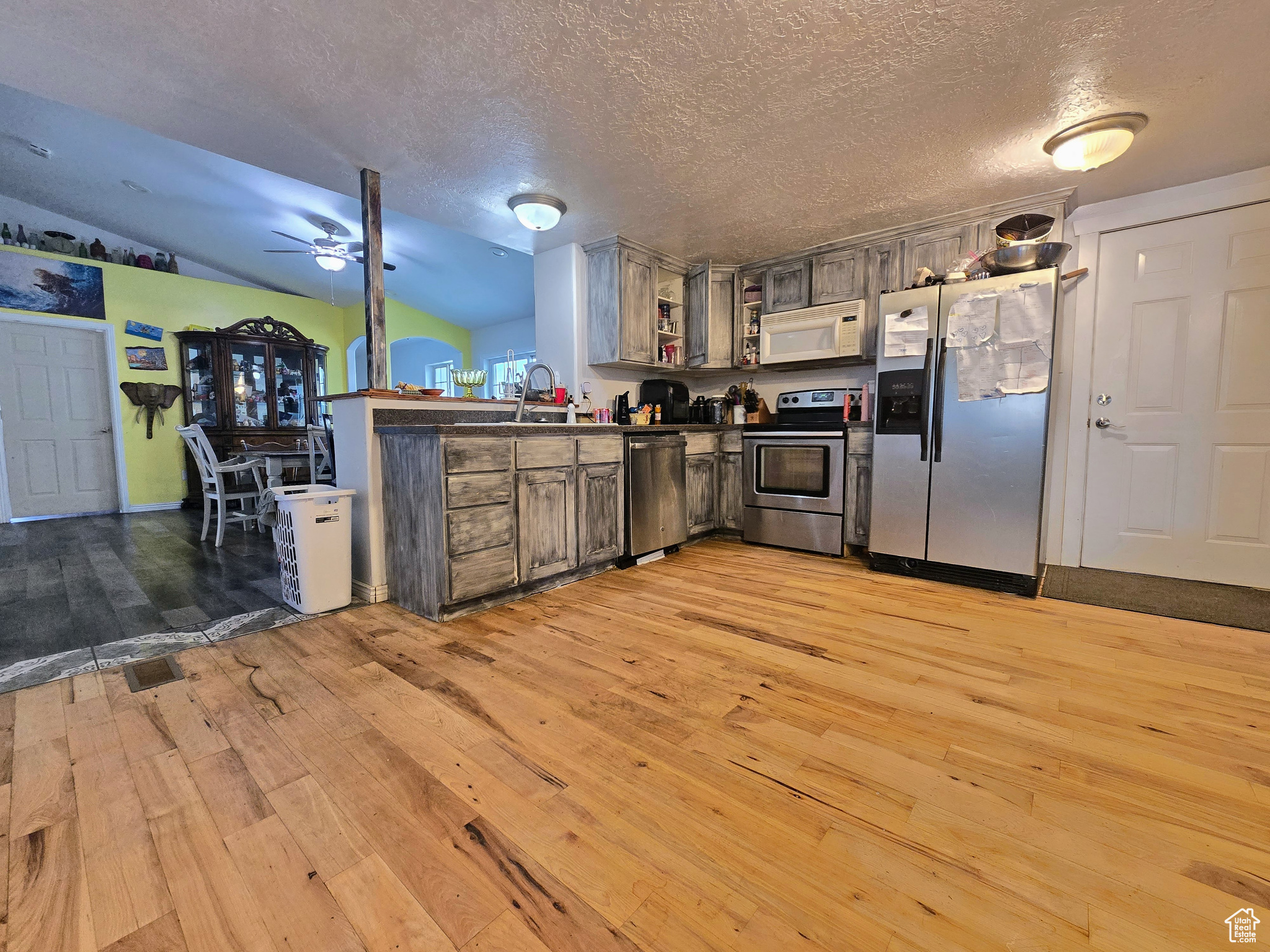 Kitchen featuring stainless steel appliances, ceiling fan, vaulted ceiling, and light wood-type flooring