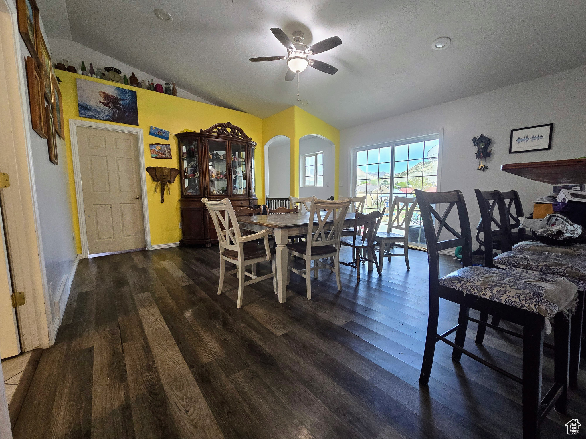 Dining room featuring ceiling fan, dark hardwood / wood-style floors, vaulted ceiling, and a textured ceiling