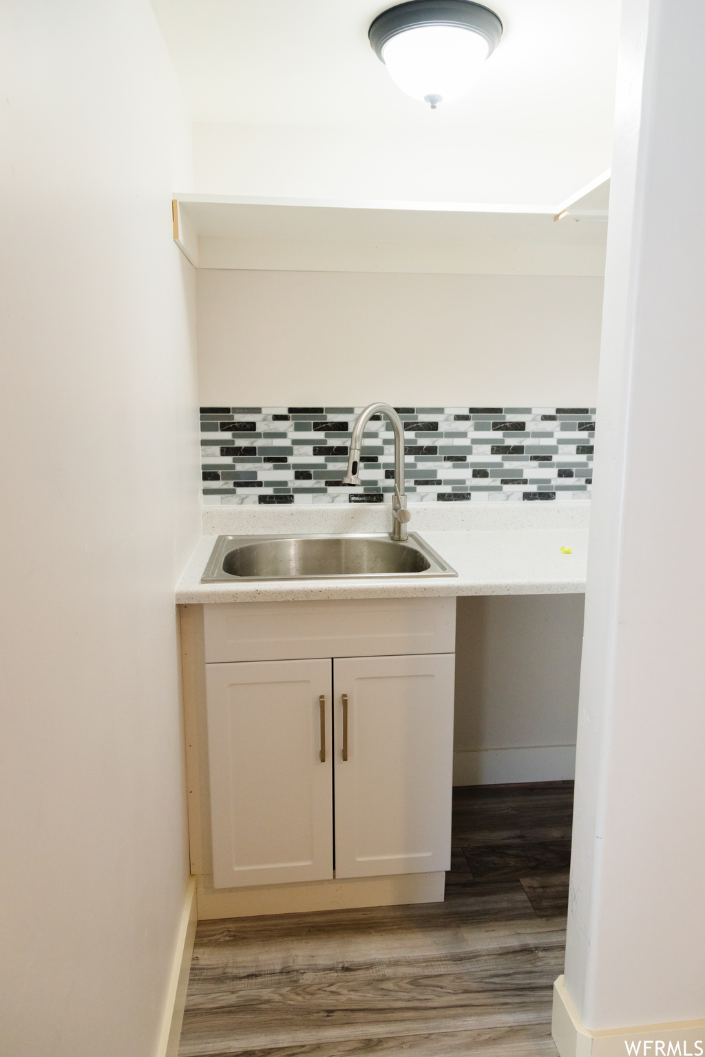 Bathroom with light hardwood flooring, backsplash, and vanity