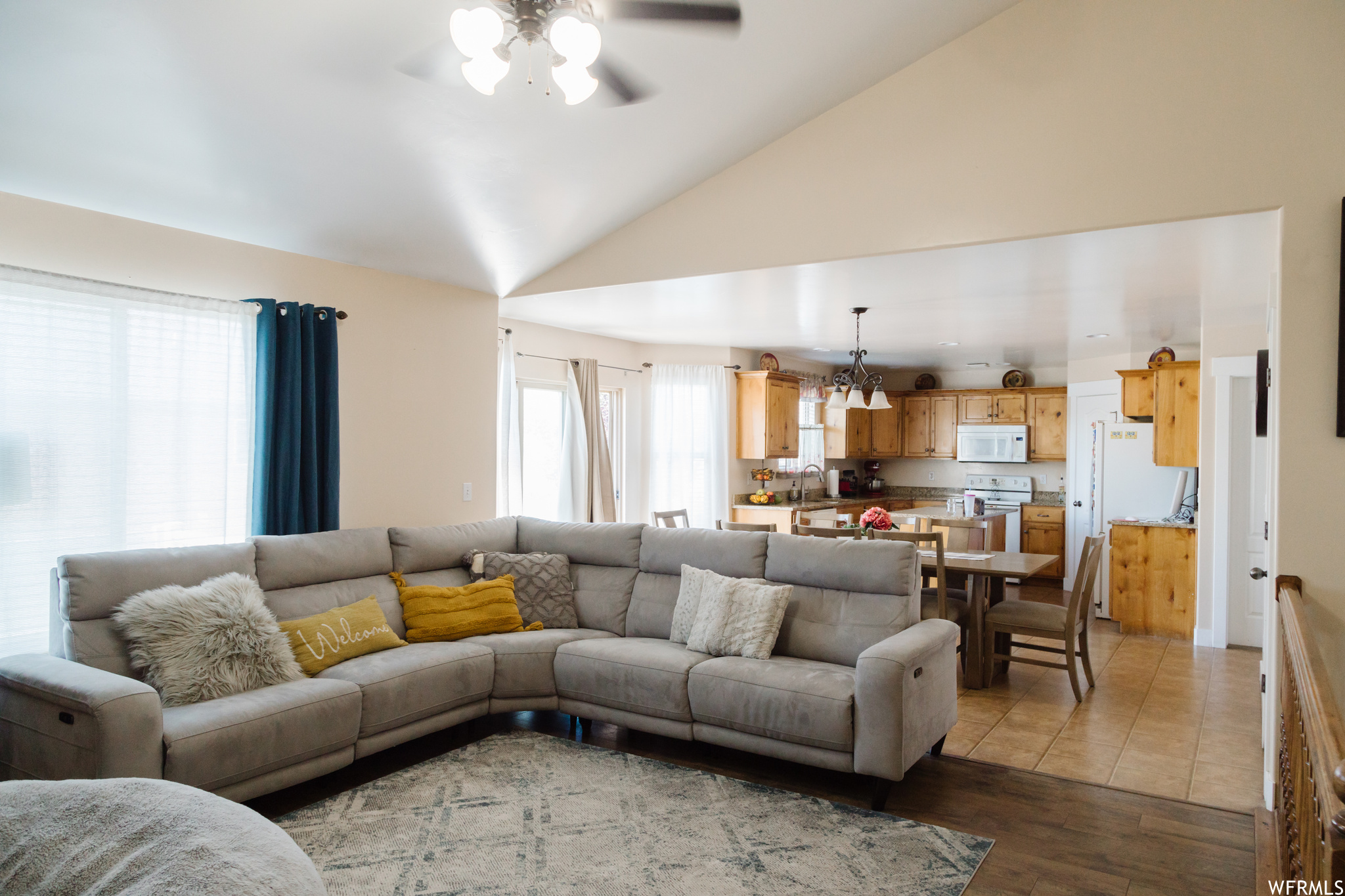 Living room featuring vaulted ceiling, a high ceiling, and light tile floors