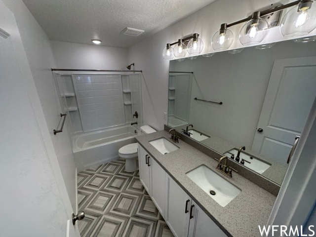 Full bathroom with dual large bowl vanity, a textured ceiling, light vinyl flooring, mirror, and tub / shower combination