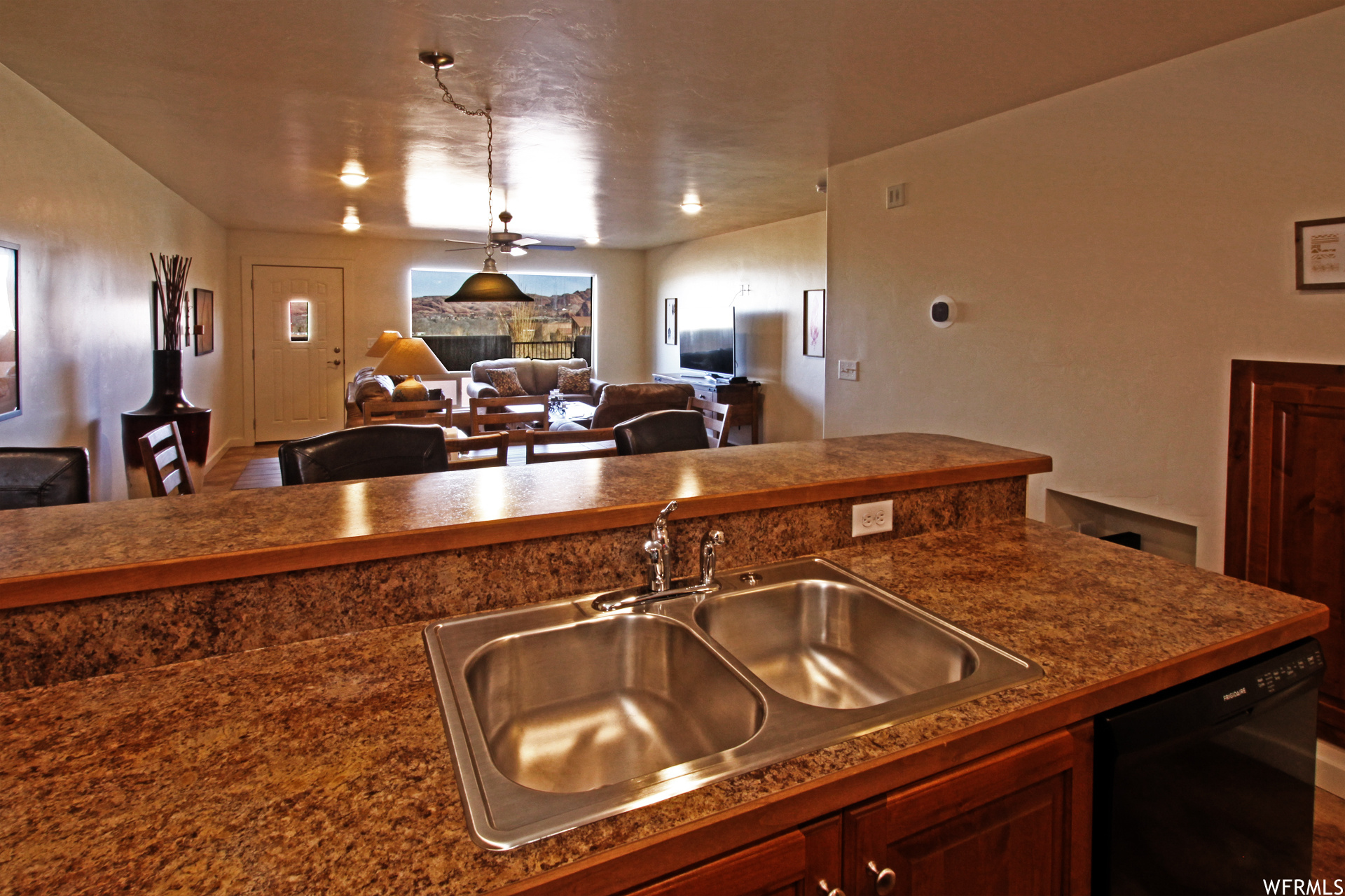 Kitchen featuring decorative light fixtures, dark brown cabinetry, dark countertops, and black dishwasher