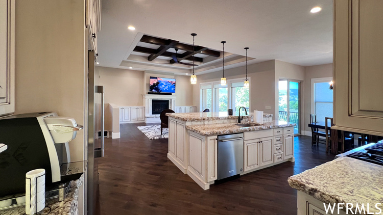 Kitchen featuring coffered ceiling, a kitchen island with sink, dark hardwood floors, dishwasher, and sink