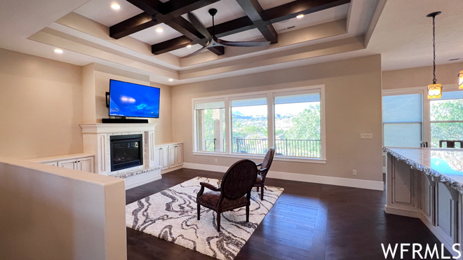 Living room featuring coffered ceiling, ceiling fan, dark hardwood floors, and beamed ceiling