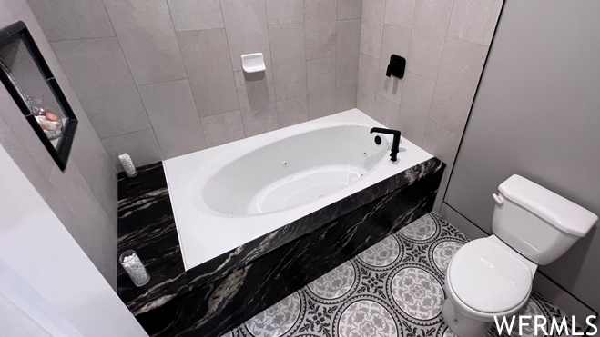 Bathroom with toilet, bathtub / shower combination, and tile flooring