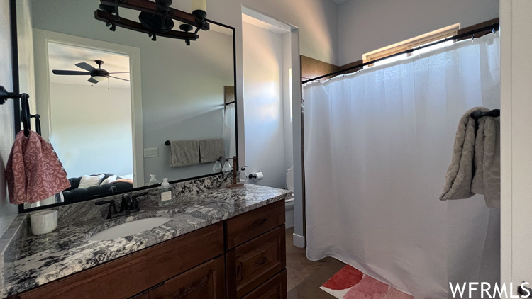 Bathroom with toilet, vanity, and ceiling fan