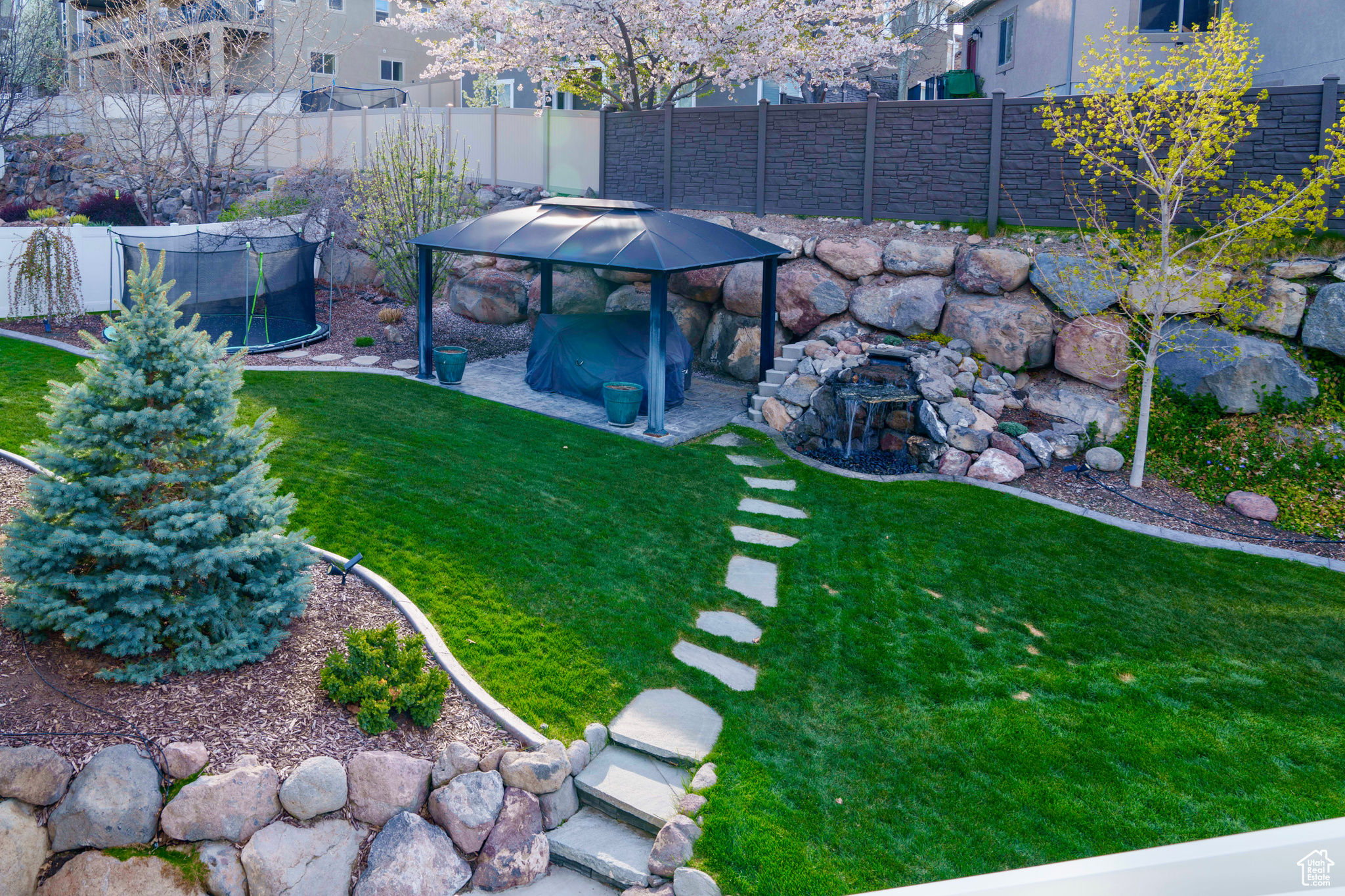 Fully landscape backyard with gazebo, waterfall and in-ground trampoline.