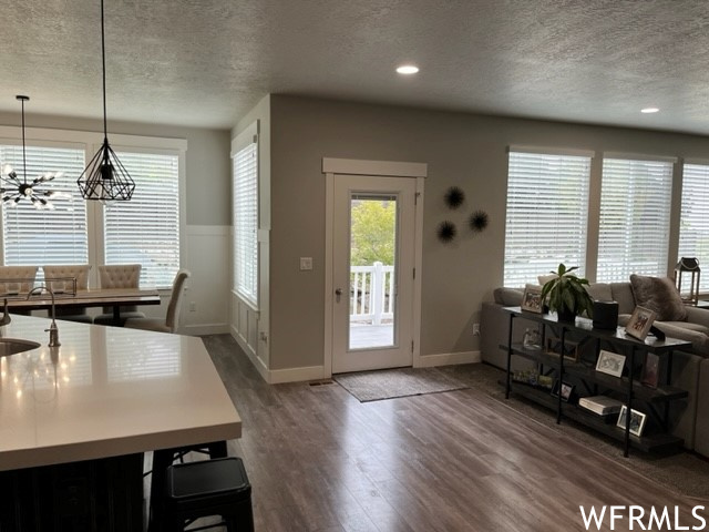 Hardwood floored foyer featuring a textured ceiling and a chandelier