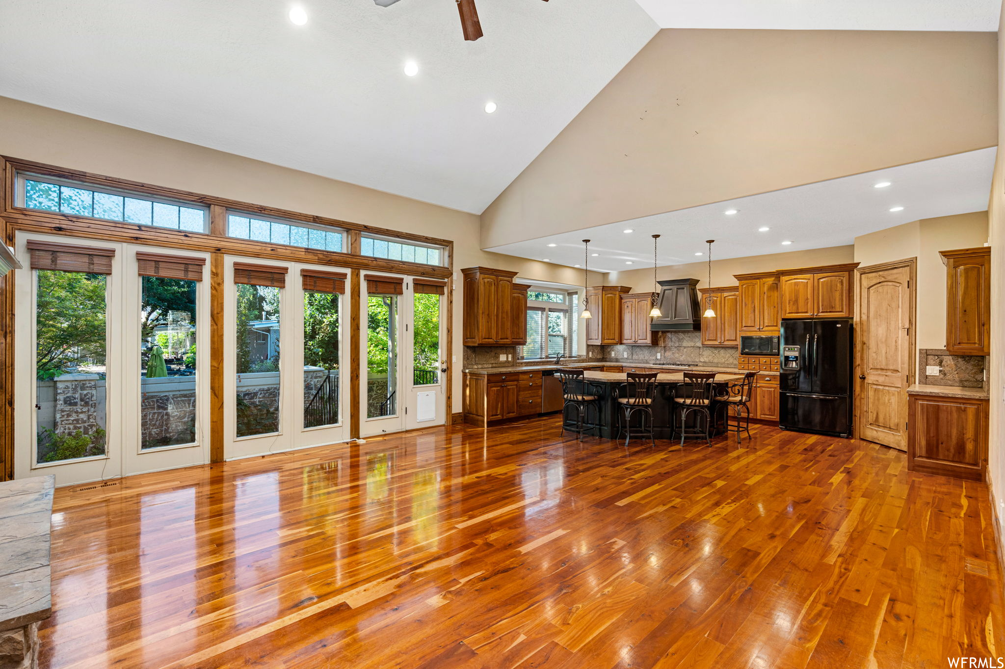 Kitchen featuring decorative light fixtures, a center island, tasteful backsplash, ceiling fan, and black appliances