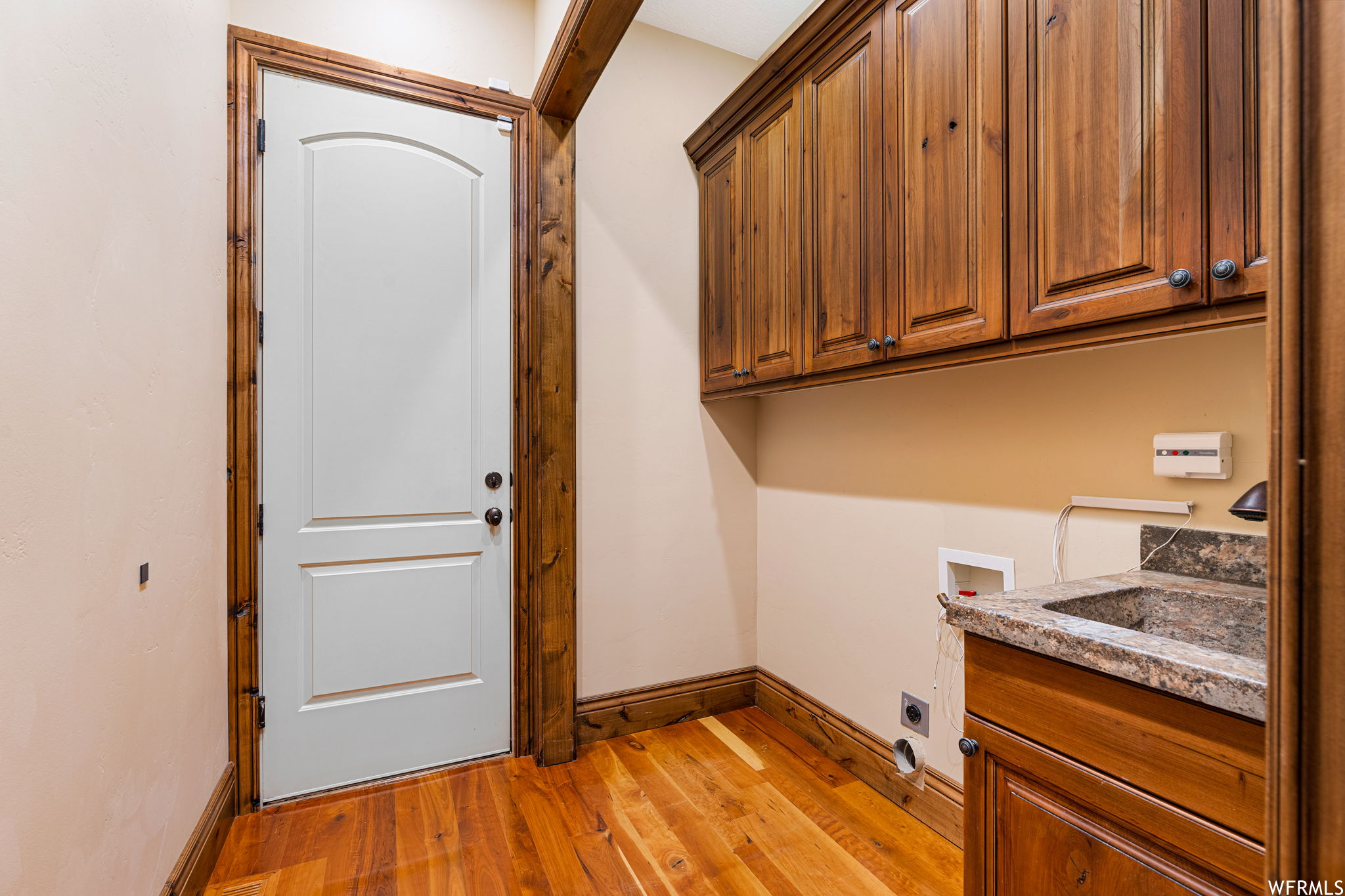 Laundry area with cabinets, hookup for an electric dryer, light hardwood floors, and hookup for a washing machine