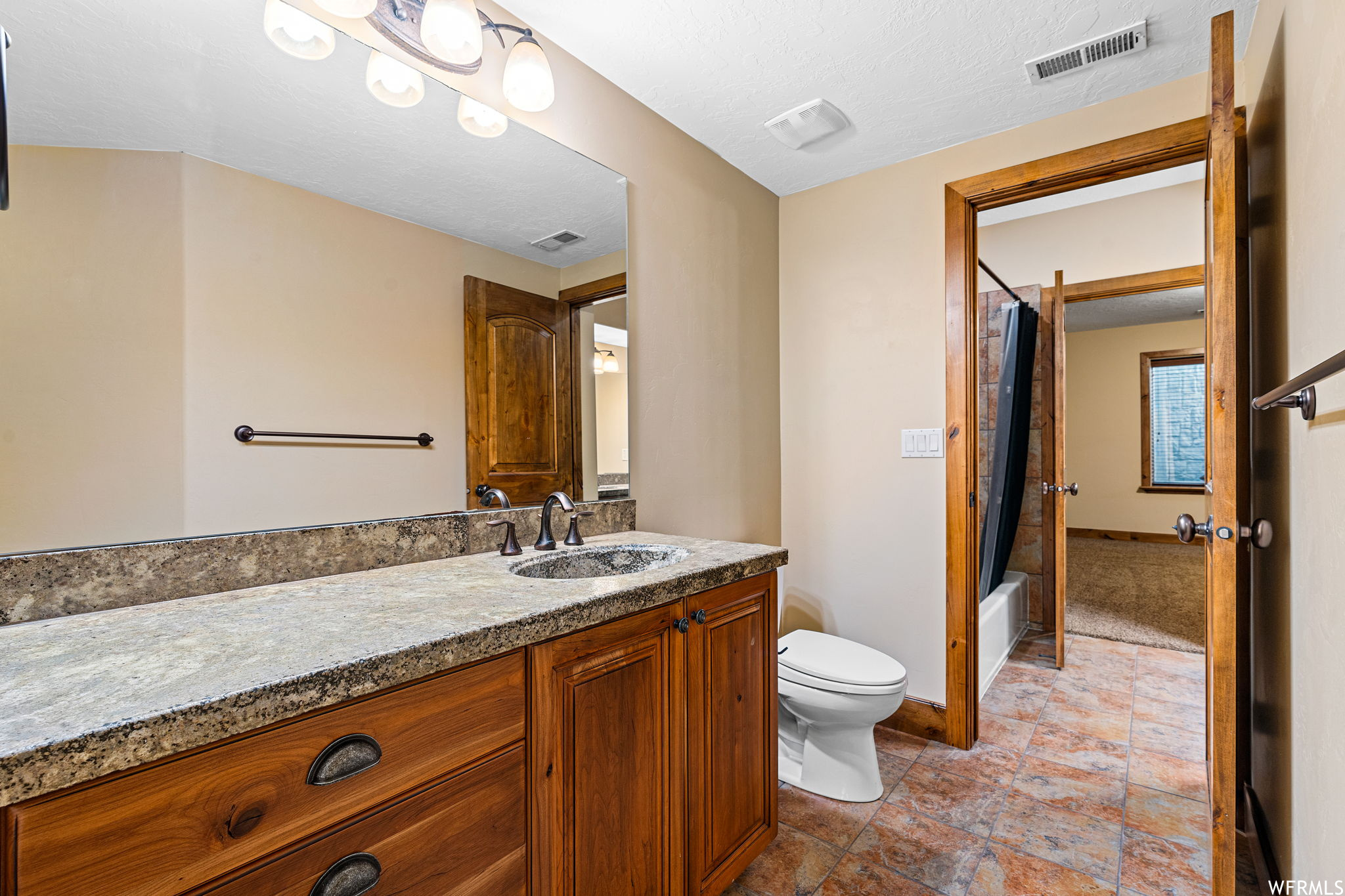 Full bathroom with tile flooring, toilet, vanity, a textured ceiling, and shower / tub combo with curtain
