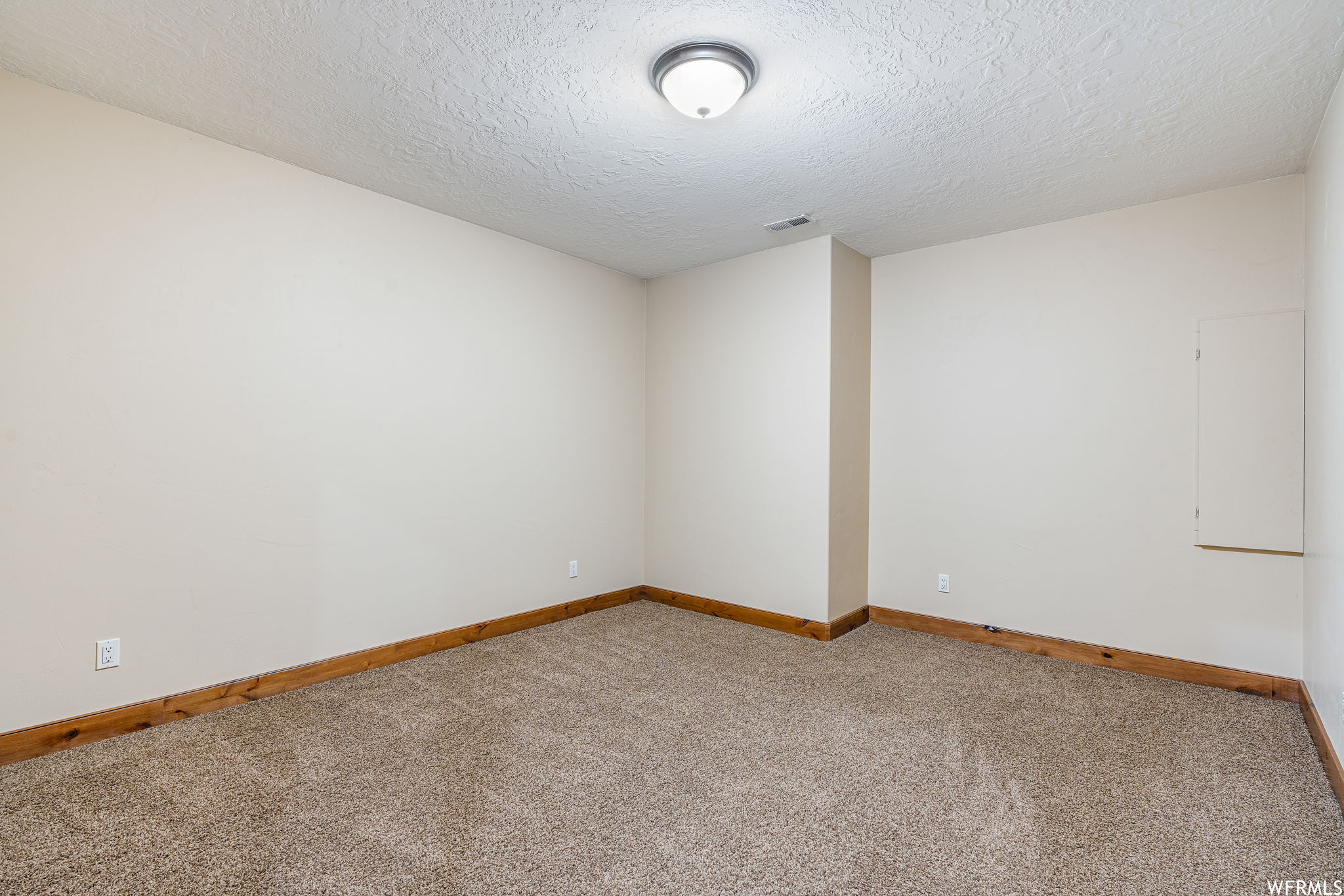 Empty room with a textured ceiling and carpet