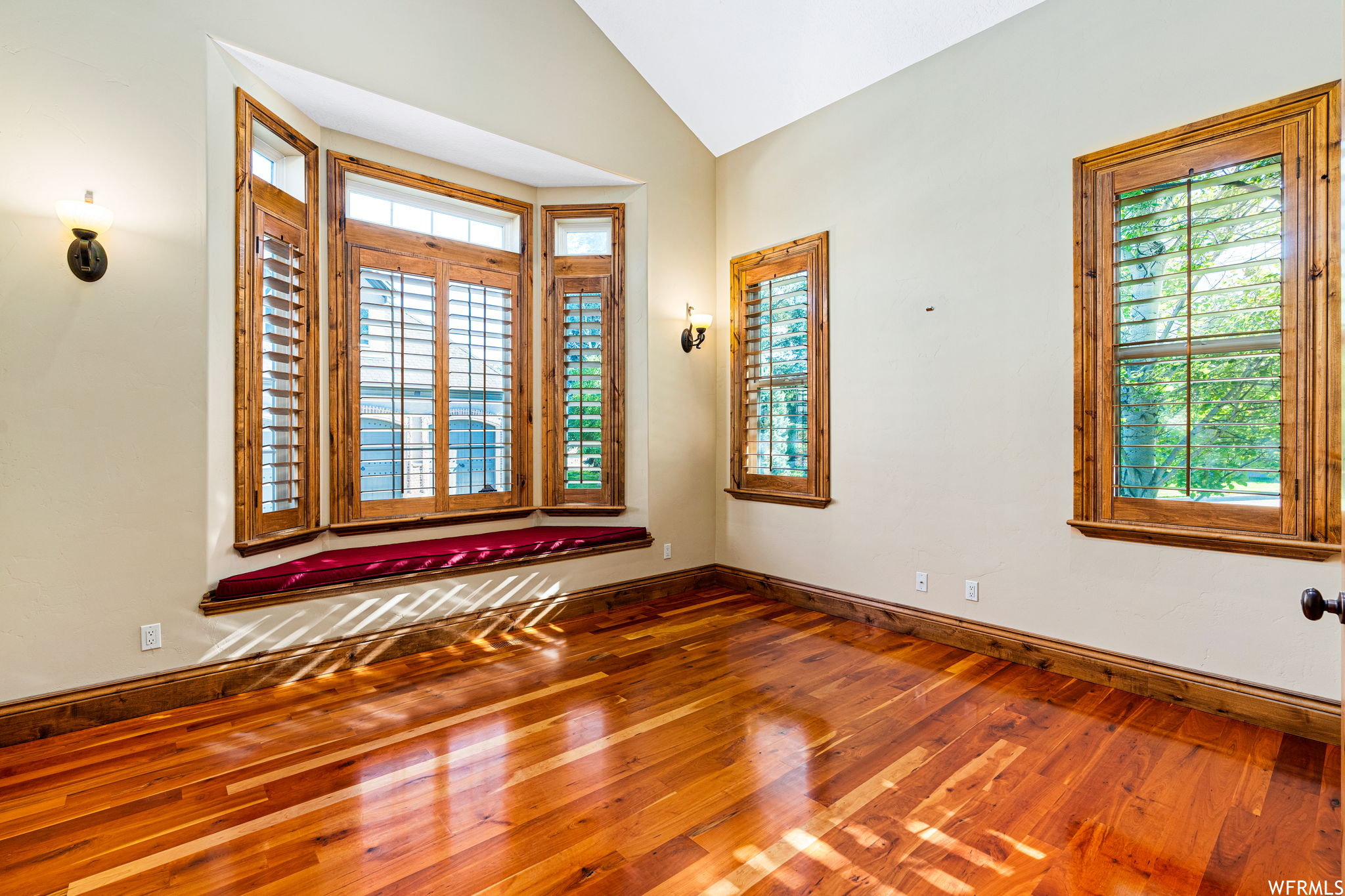 Hardwood floored spare room featuring lofted ceiling