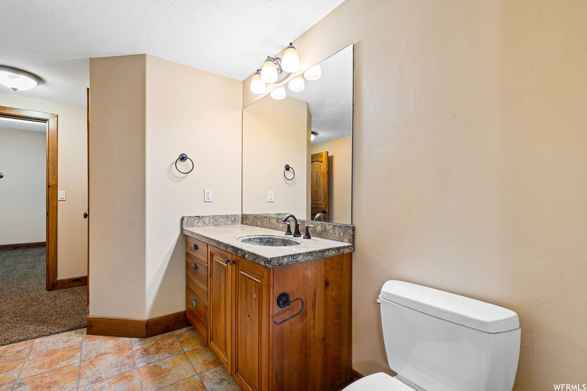 Bathroom featuring toilet, vanity, and tile flooring