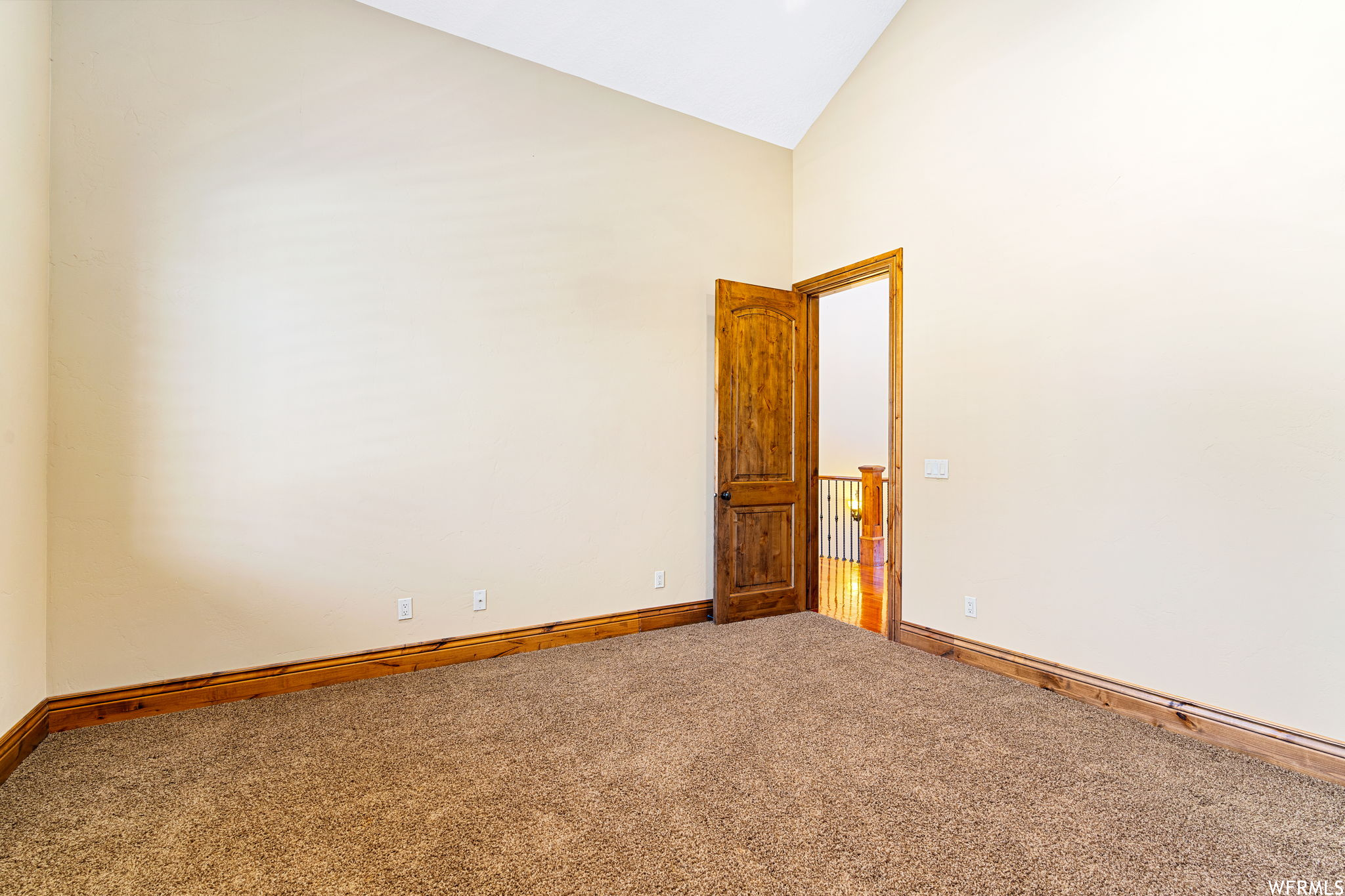 Empty room with vaulted ceiling high and carpet