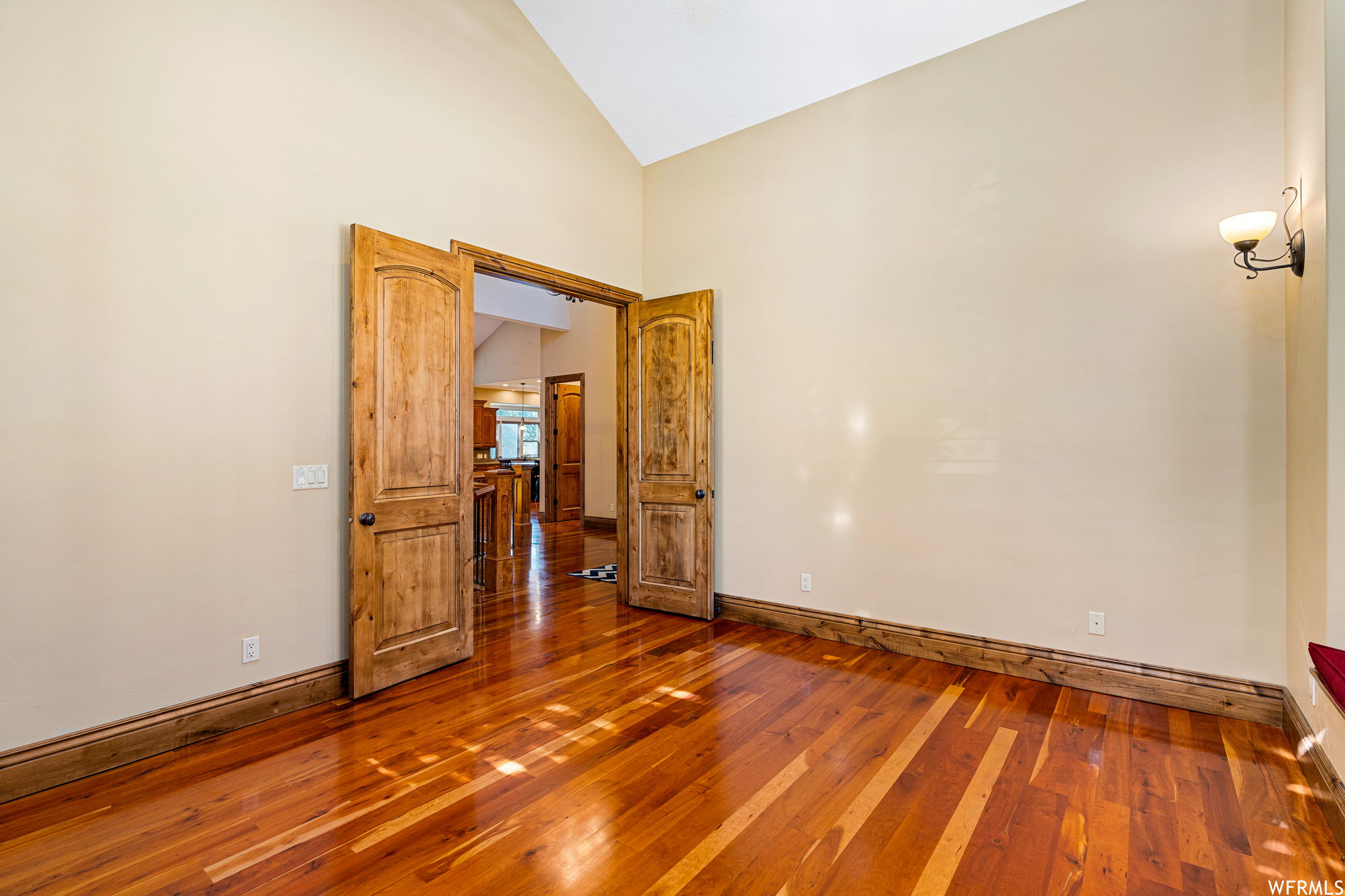 Unfurnished room featuring dark hardwood floors and vaulted ceiling high