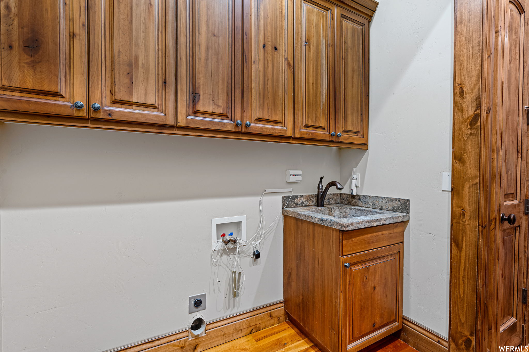 Washroom featuring cabinets, light hardwood flooring, hookup for an electric dryer, hookup for a washing machine, and sink