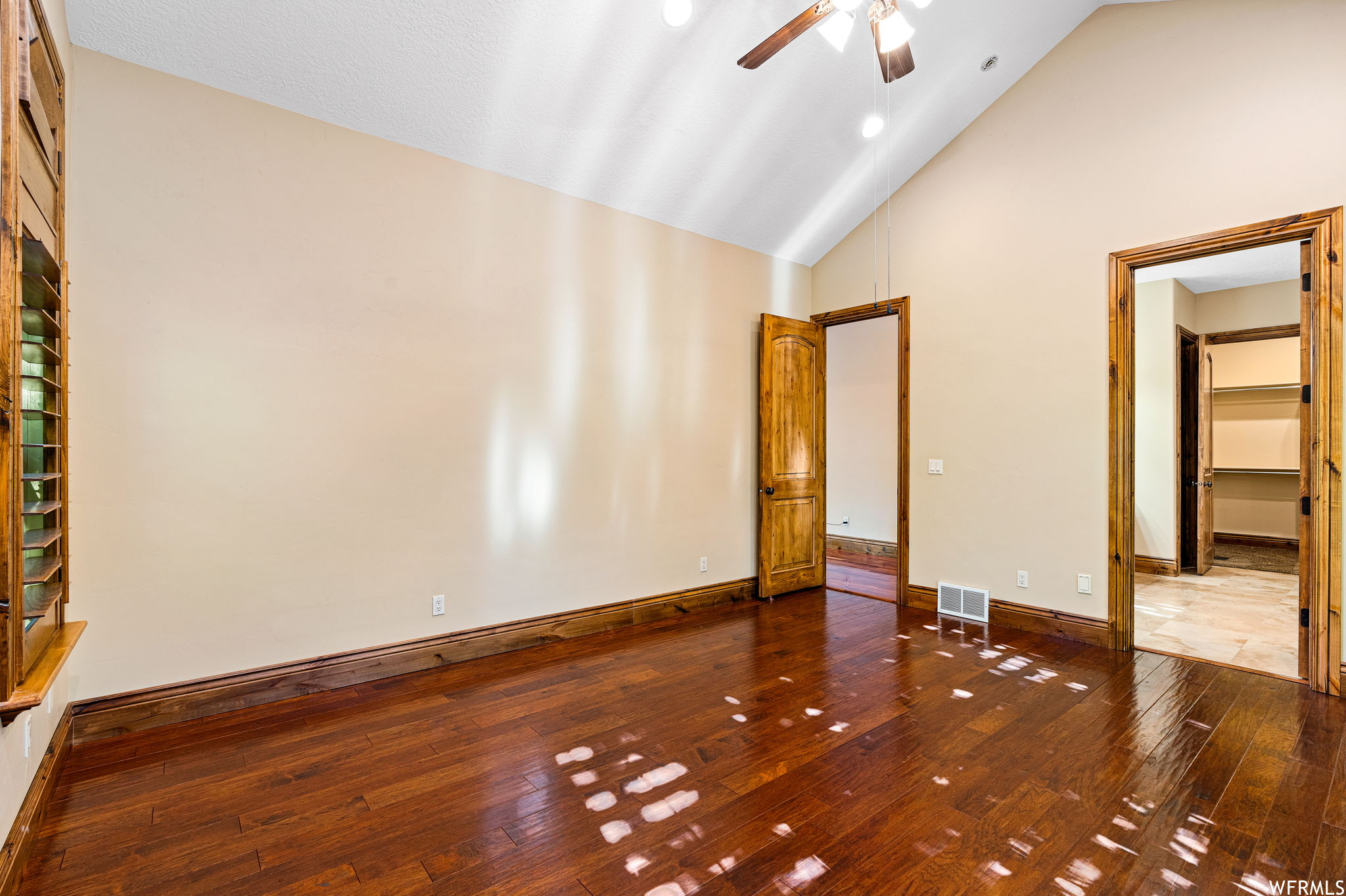 Unfurnished bedroom featuring ceiling fan, a spacious closet, dark tile floors, a closet, and vaulted ceiling high