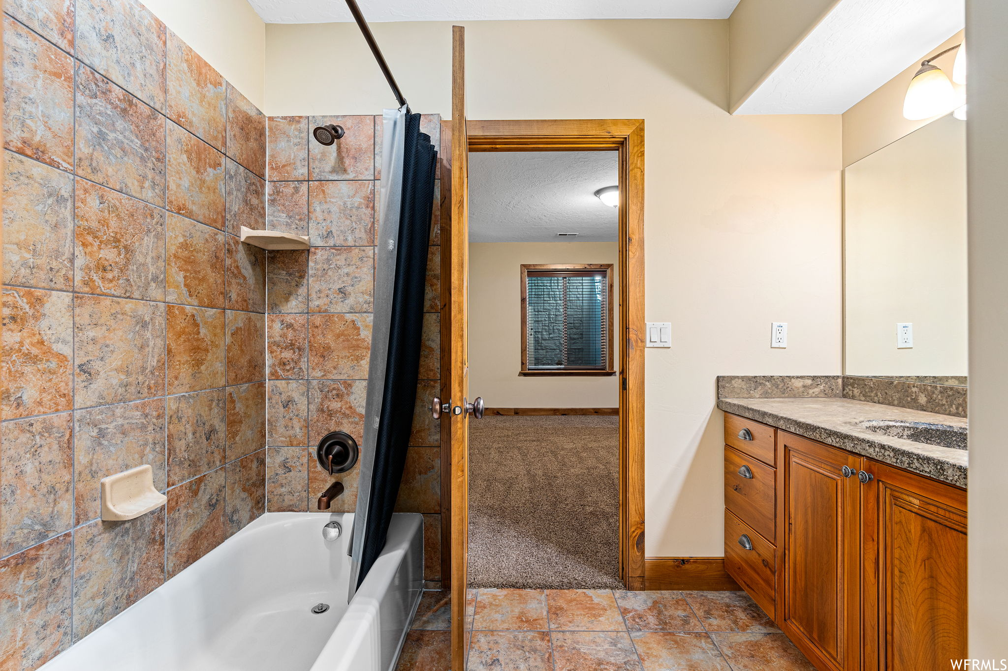 Bathroom featuring shower / bathtub combination with curtain, vanity, and tile floors