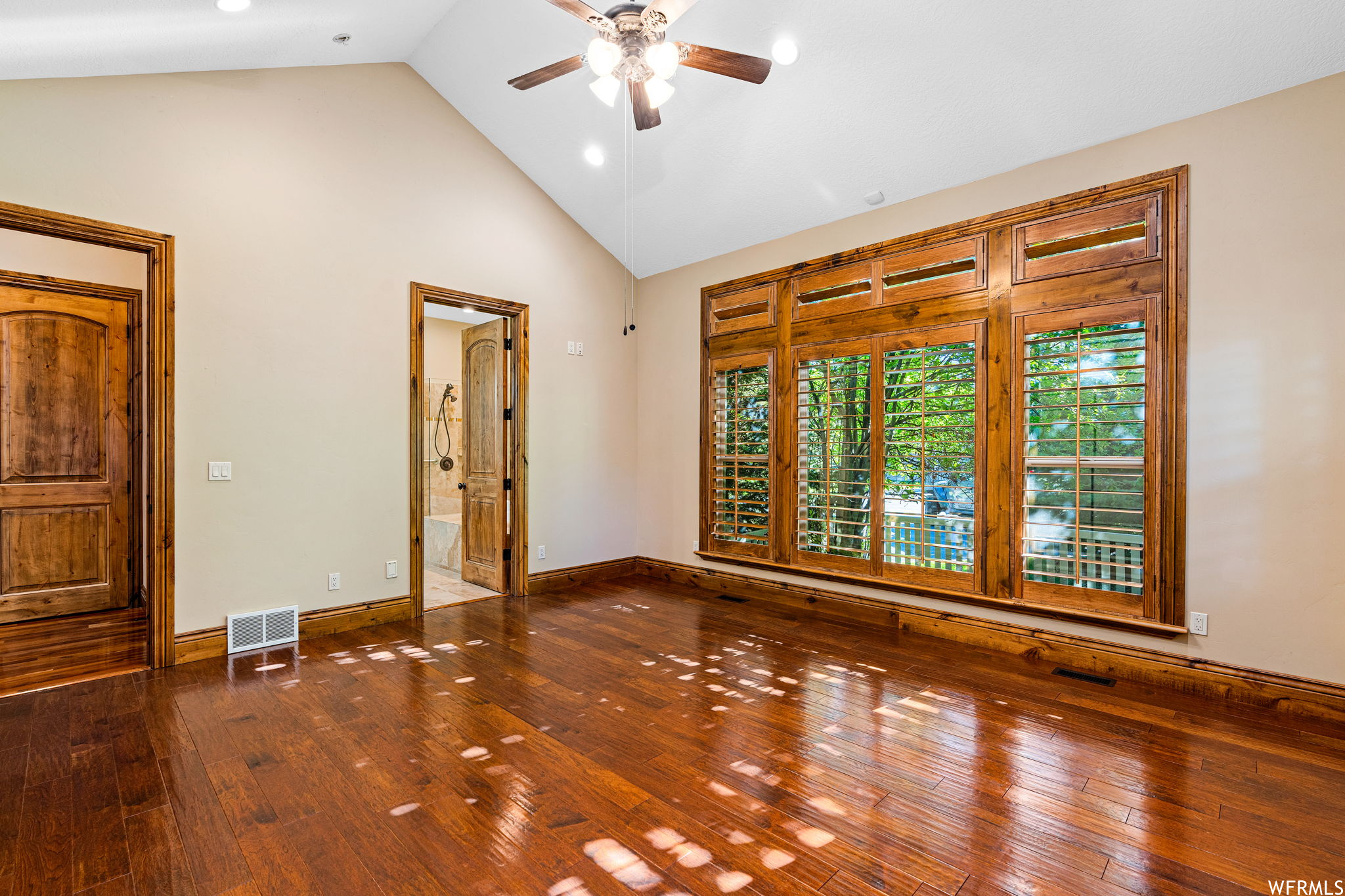 Hardwood floored spare room featuring vaulted ceiling high and ceiling fan