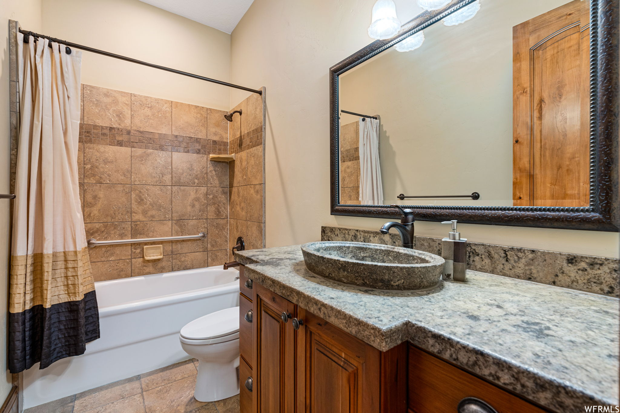 Full bathroom with tile floors, toilet, vanity with extensive cabinet space, and shower / bath combo with shower curtain