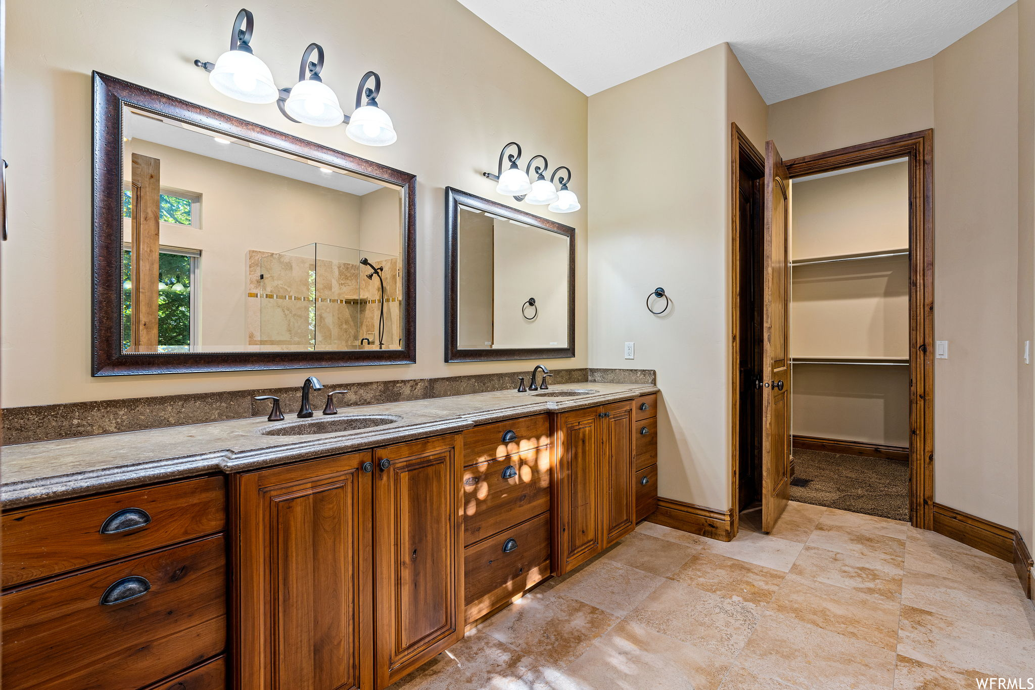 Bathroom featuring a shower, double sink vanity, and tile floors