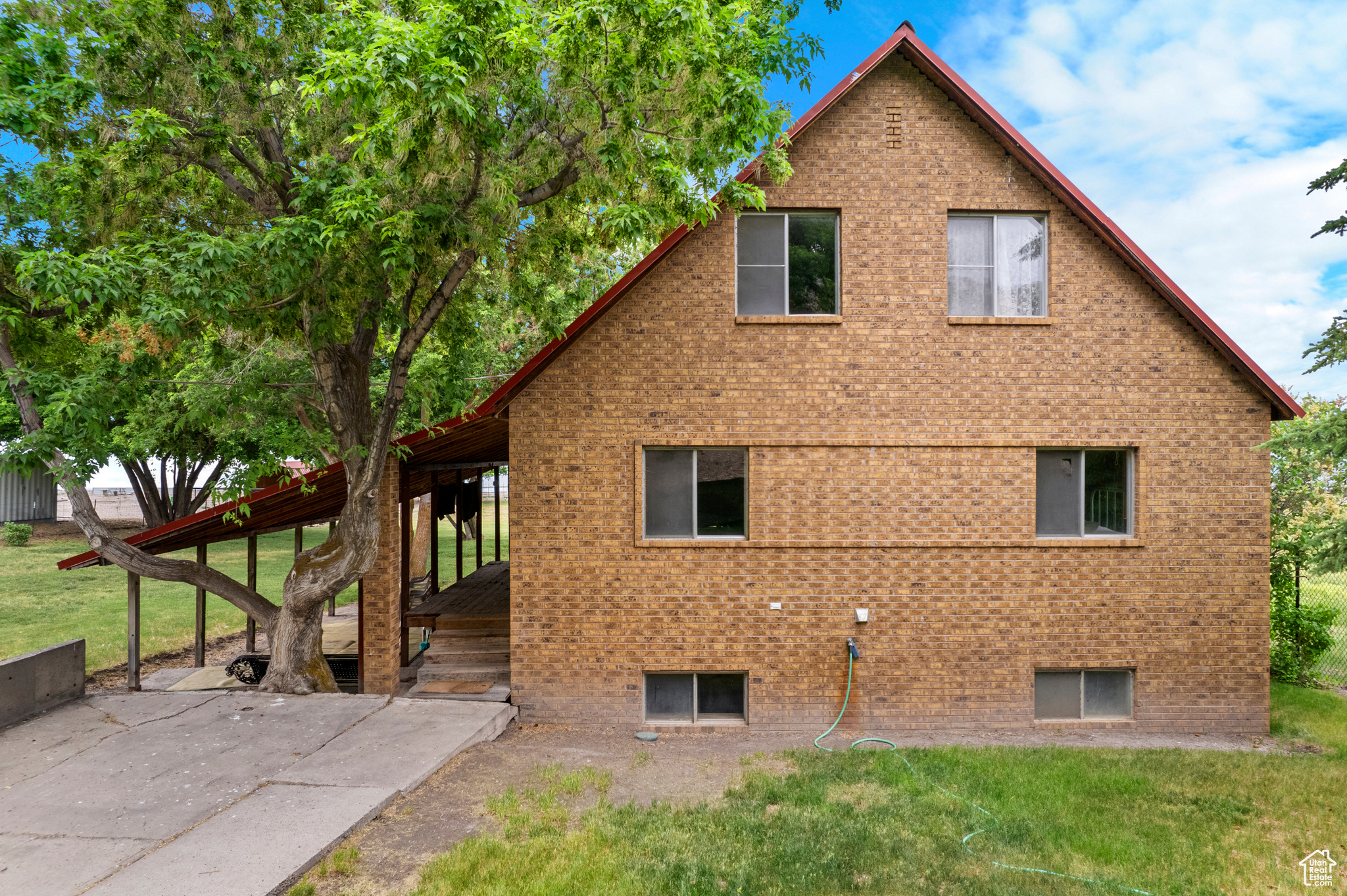 View of side of property featuring a lawn and a wooden deck