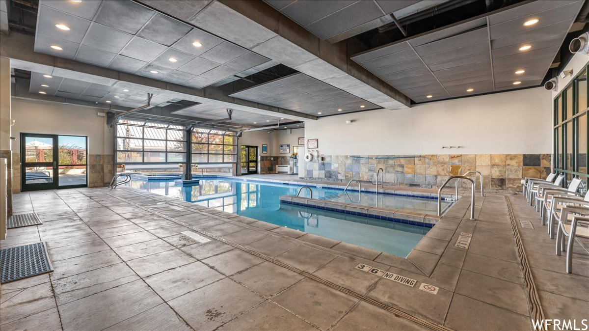 View of swimming pool featuring a patio area and an indoor hot tub